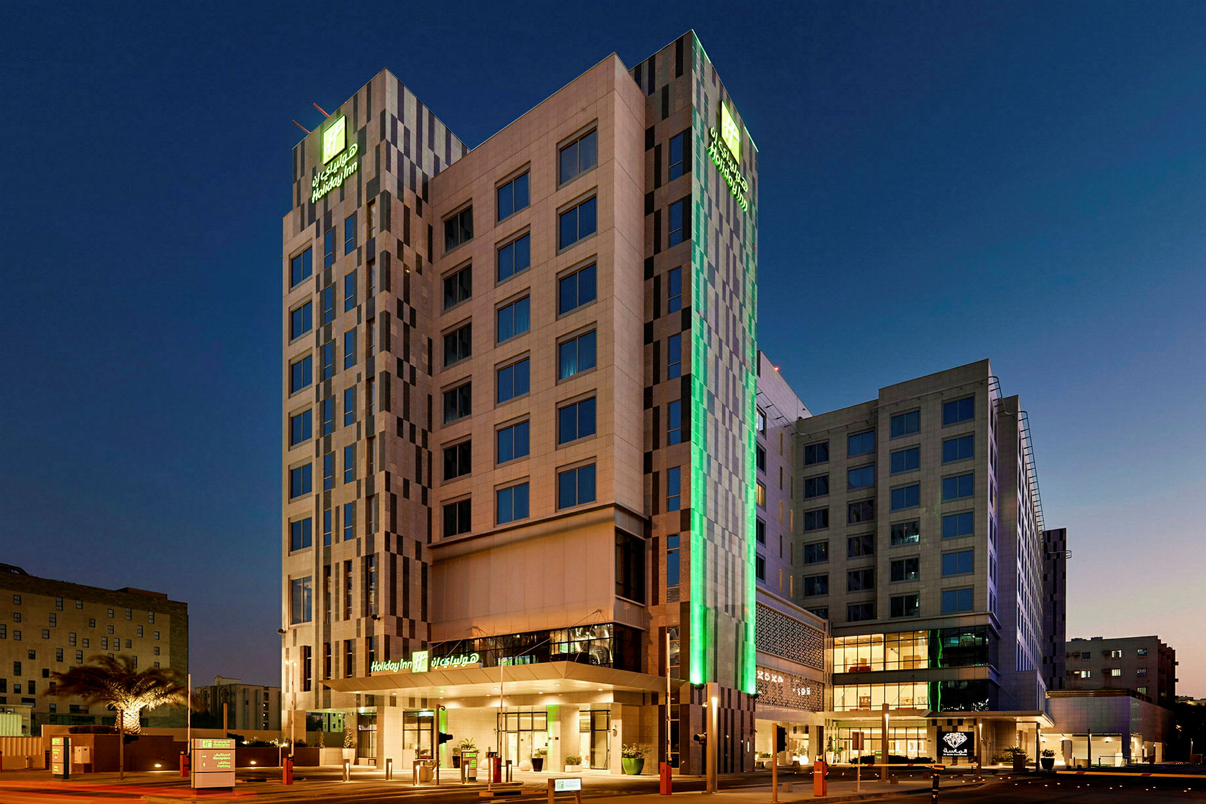 En høj bygning med oplyste vinduer og et tydeligt skilt, der viser hotellets navn, fotograferet i skumringen. (AI-genereret tekst)