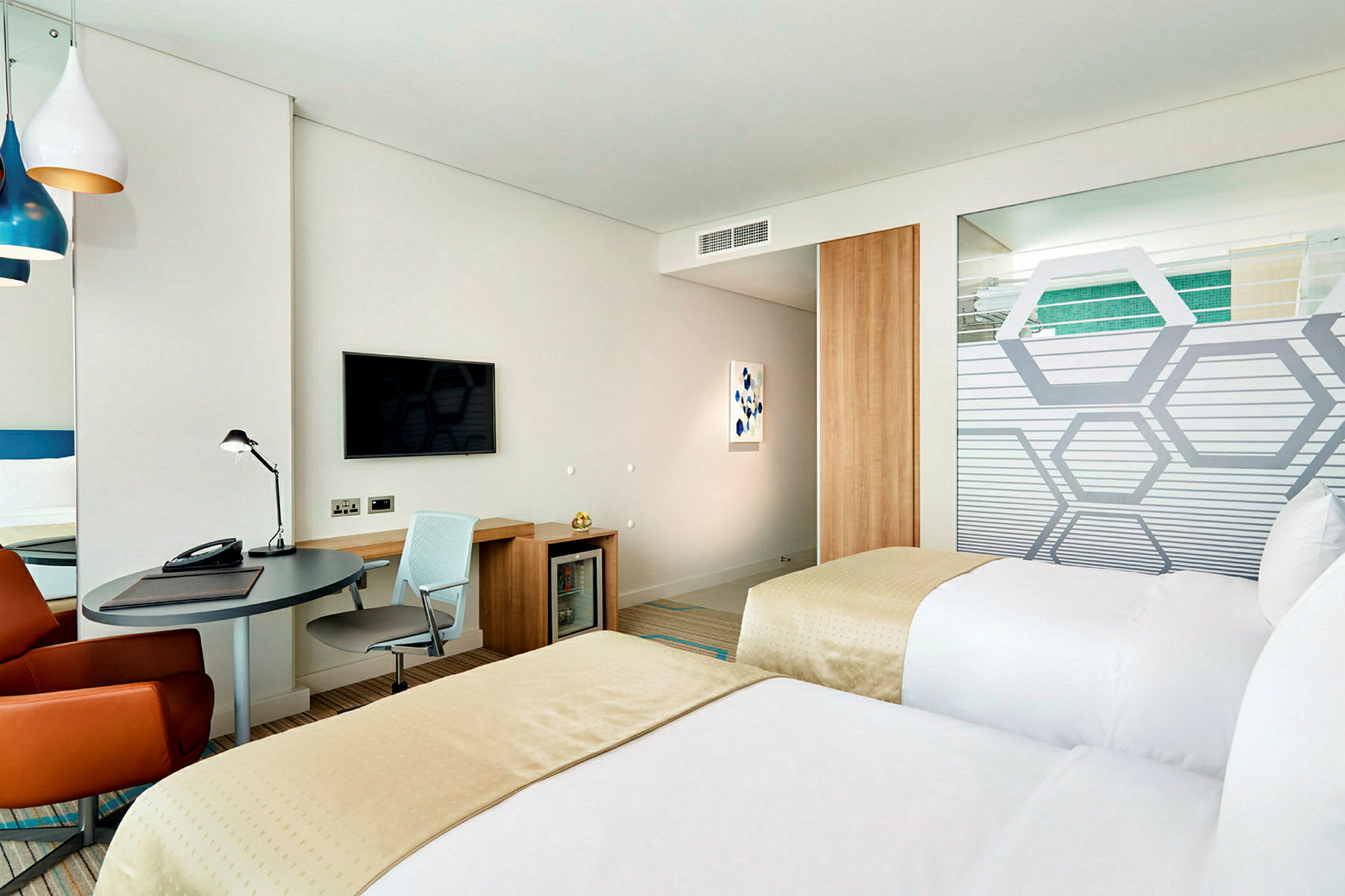 Hotelværelse med to enkeltsenge, skrivebord og væg-tv. (AI-genereret tekst)