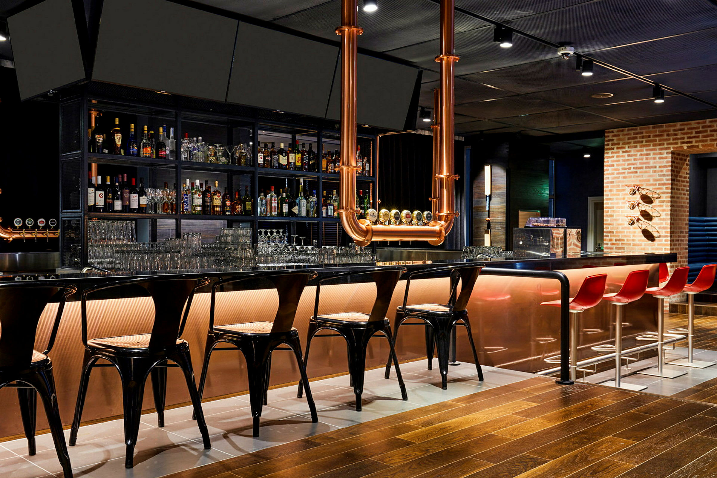 En moderne bar med en lang bardisk, høje stole og flasker opstillet på hylder bagved. (AI-genereret tekst)