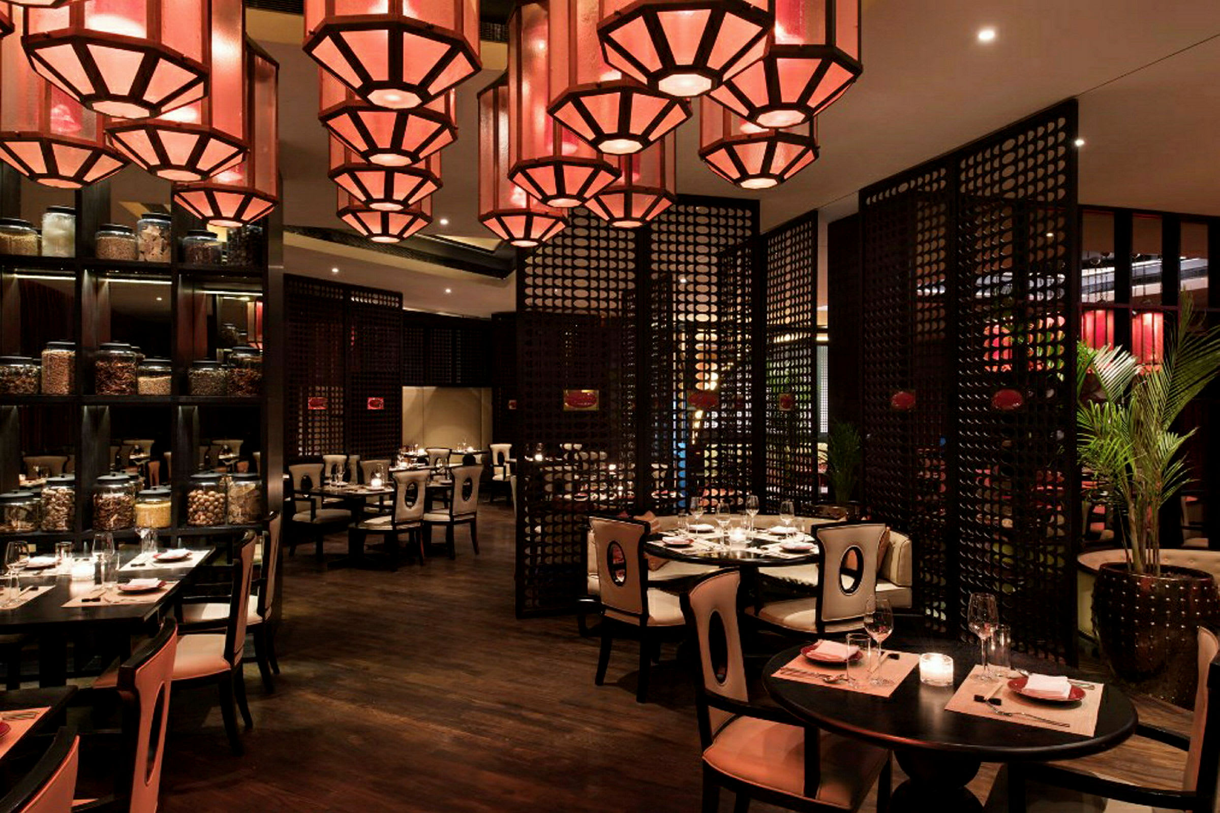 En restaurant med elegant interiør, borde med duge og stole samt dekorative røde lamper i loftet. (AI-genereret tekst)