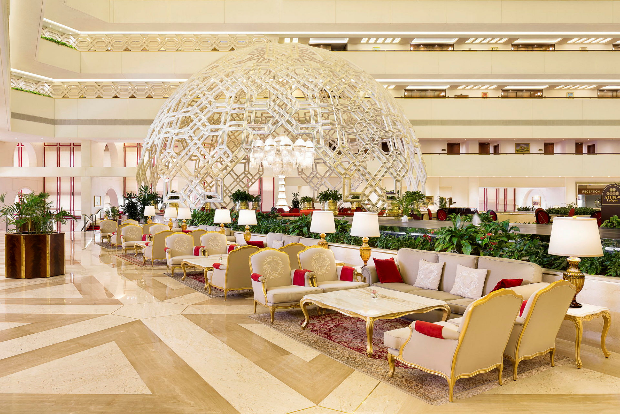 En elegant hotellobby med luksuriøse siddepladser, en dekorativ geometrisk struktur og velplejede planter. (AI-genereret tekst)