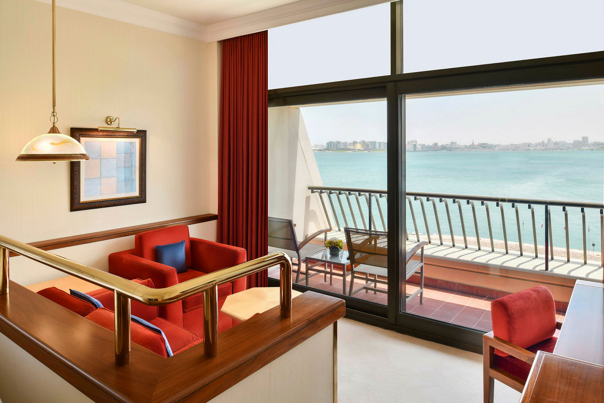 En moderne hotelsuite med siddeområde, store vinduer og udsigt over havet. (AI-genereret tekst)