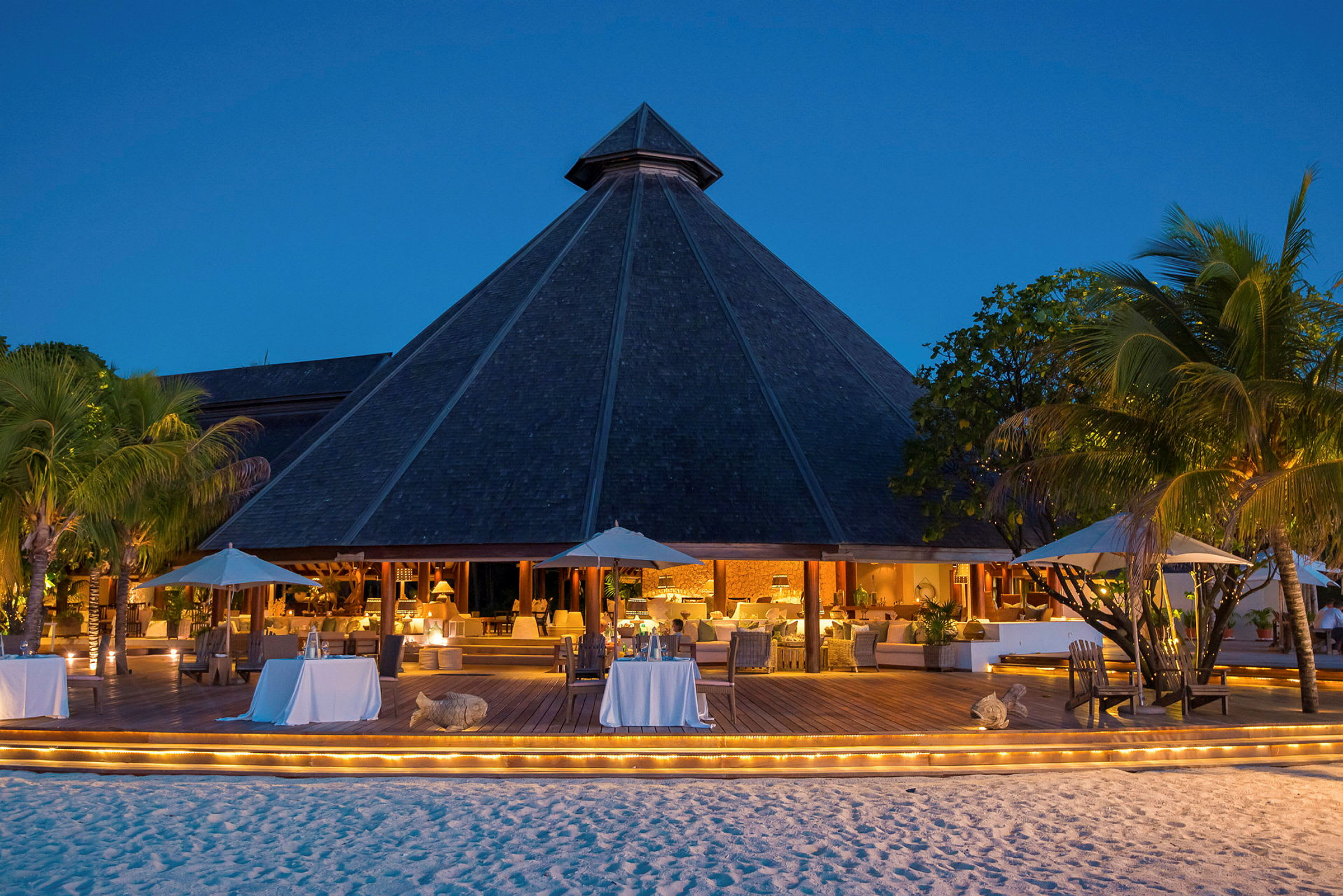 En restaurant med siddepladser udendørs ved stranden om aftenen. (AI-genereret tekst)