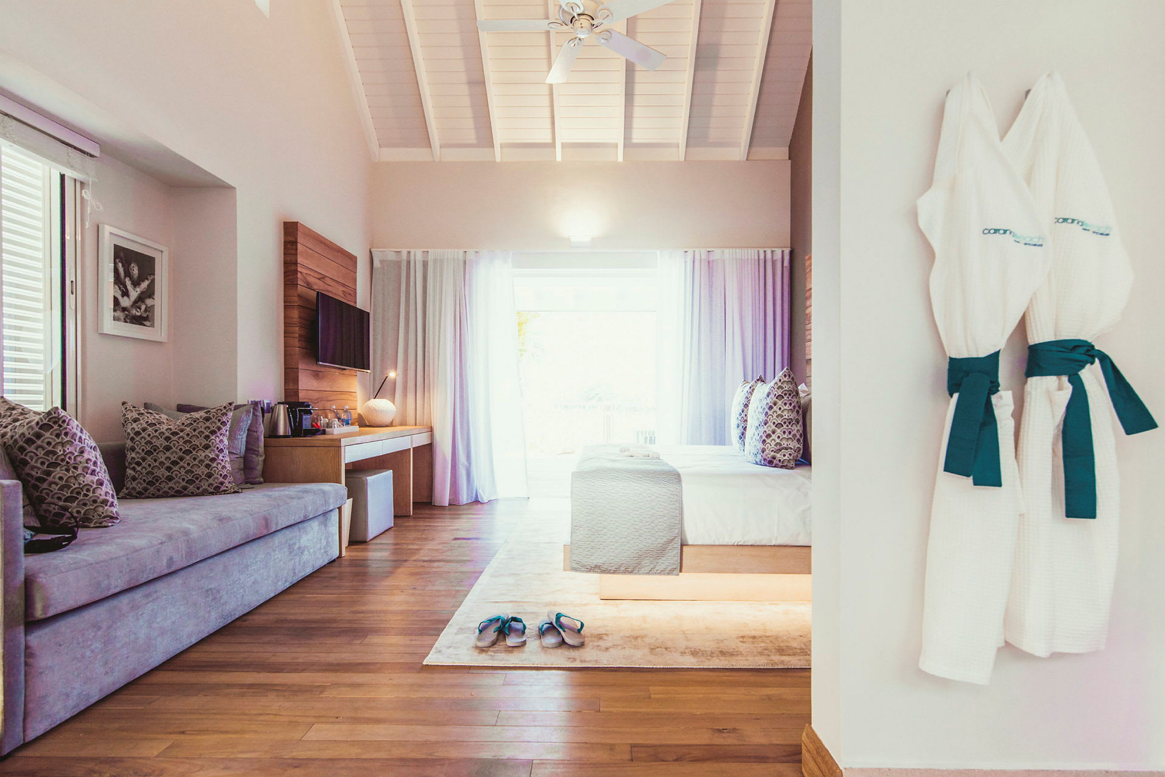 Et hotelværelse med sofa, seng og badekåber hængende på væggen. (AI-genereret tekst)
