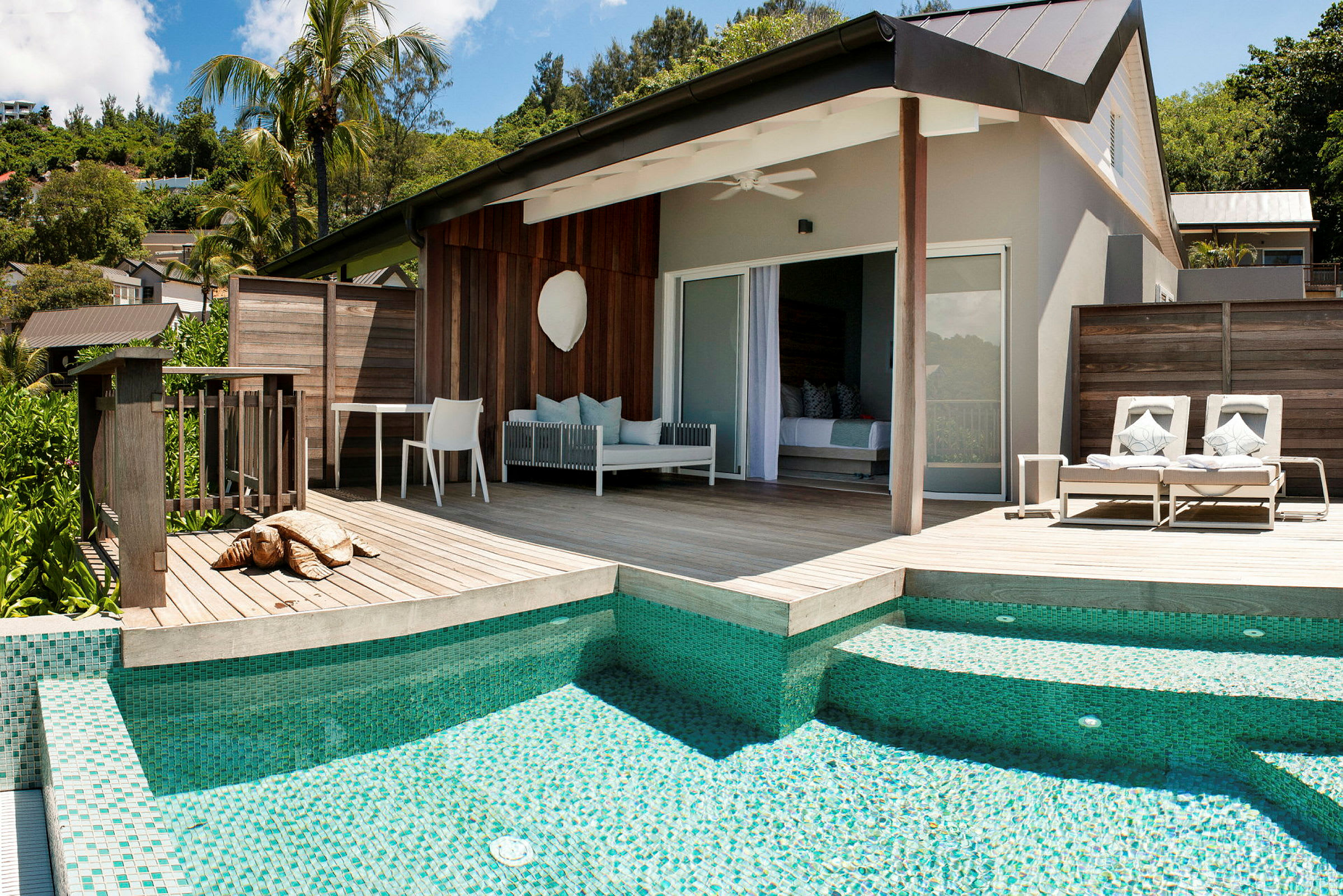 Moderne bungalow med træterrasse, liggestole og pool. (AI-genereret tekst)