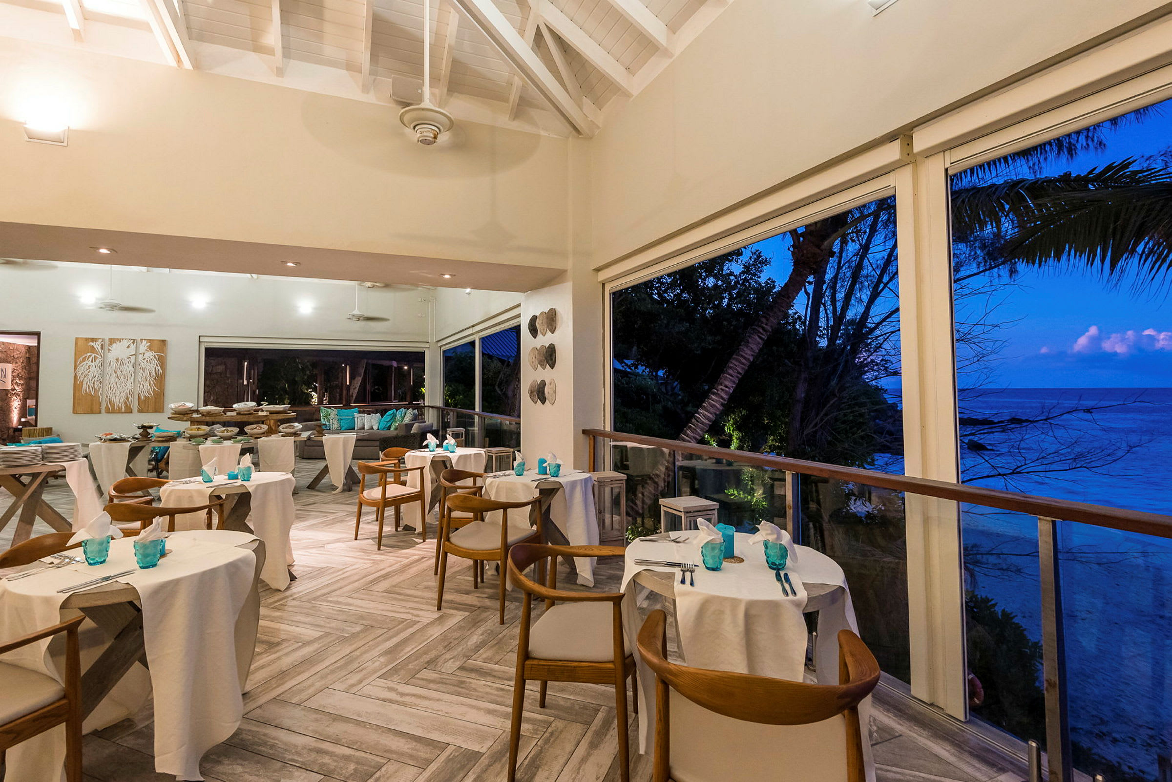 Et restaurantområde med dækkede borde og udsigt over havet ved solnedgang. (AI-genereret tekst)