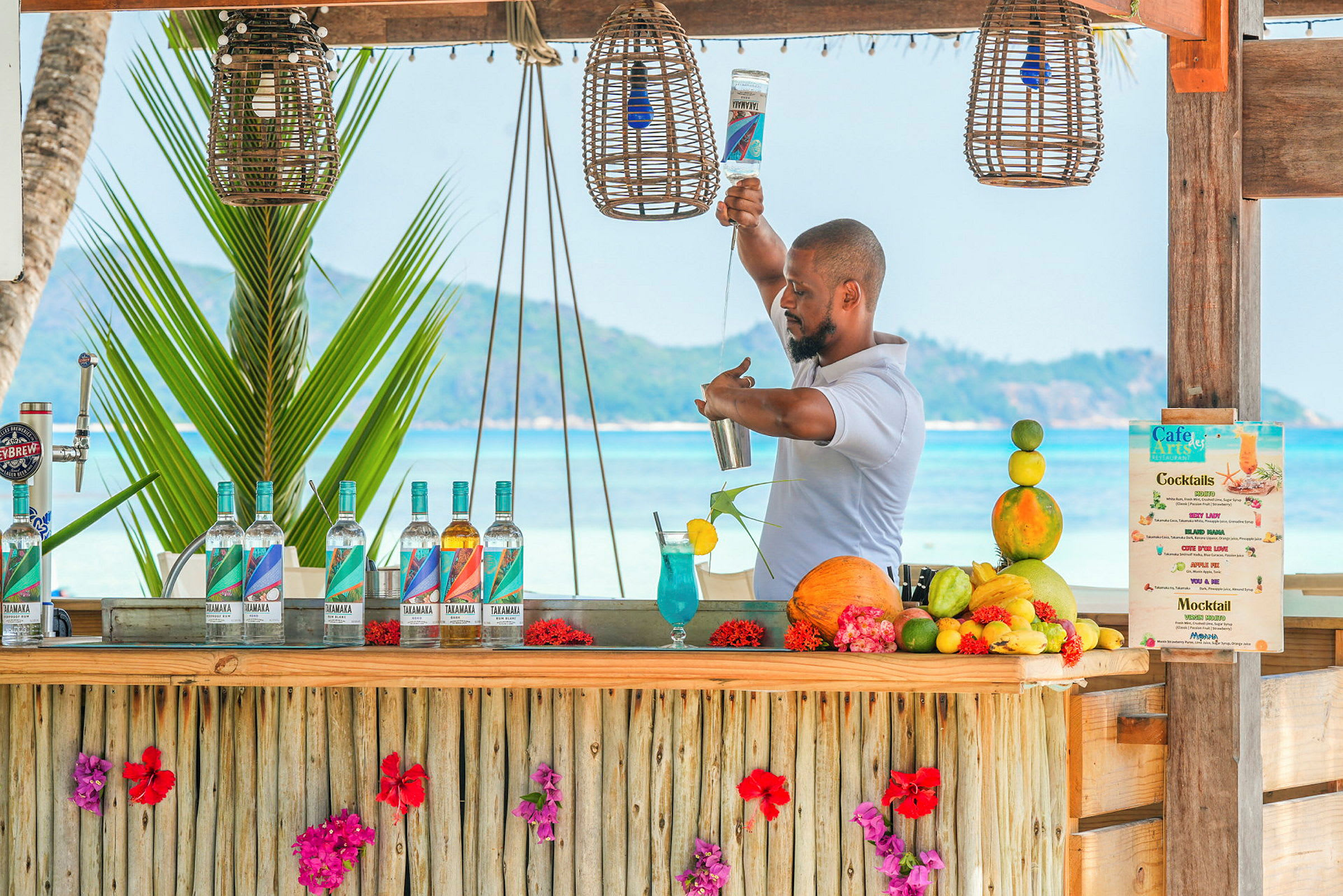 En strandbar dekoreret med blomster, hvor cocktails laves. (AI-genereret tekst)