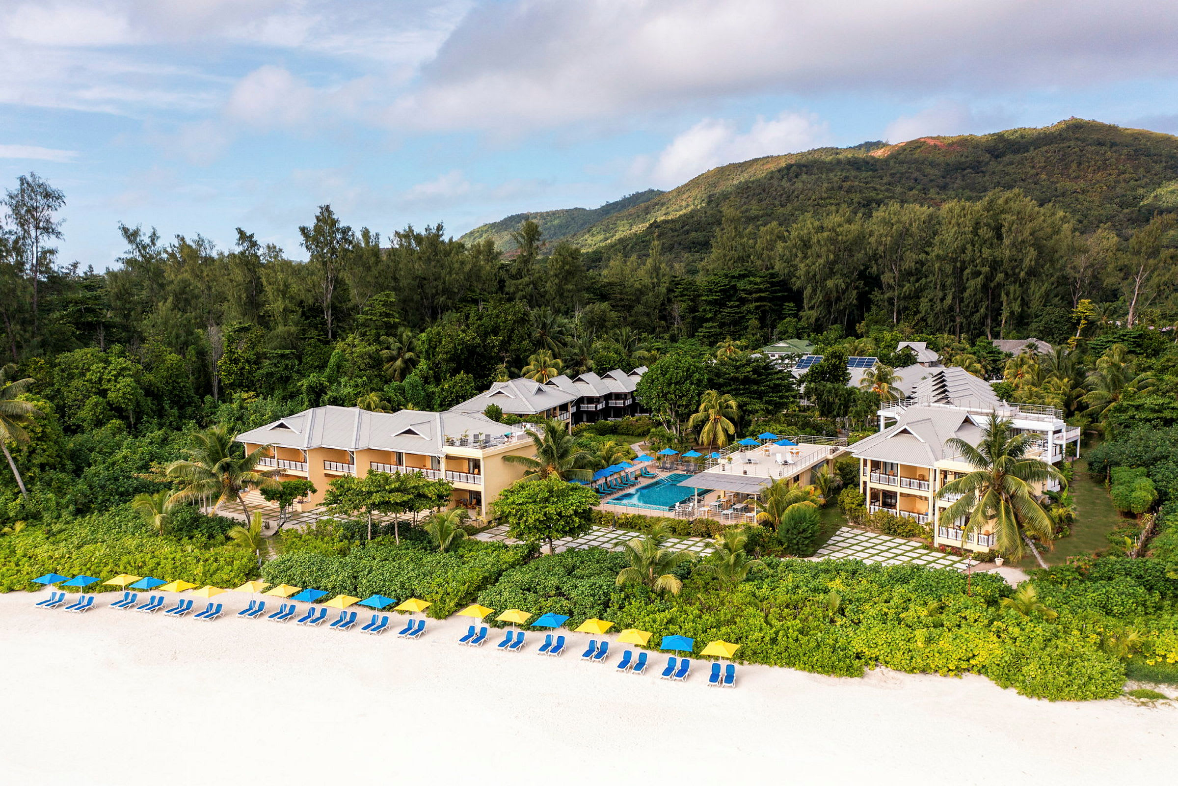 Hotelbygninger med en pool i tropisk miljø ved stranden. (AI-genereret tekst)