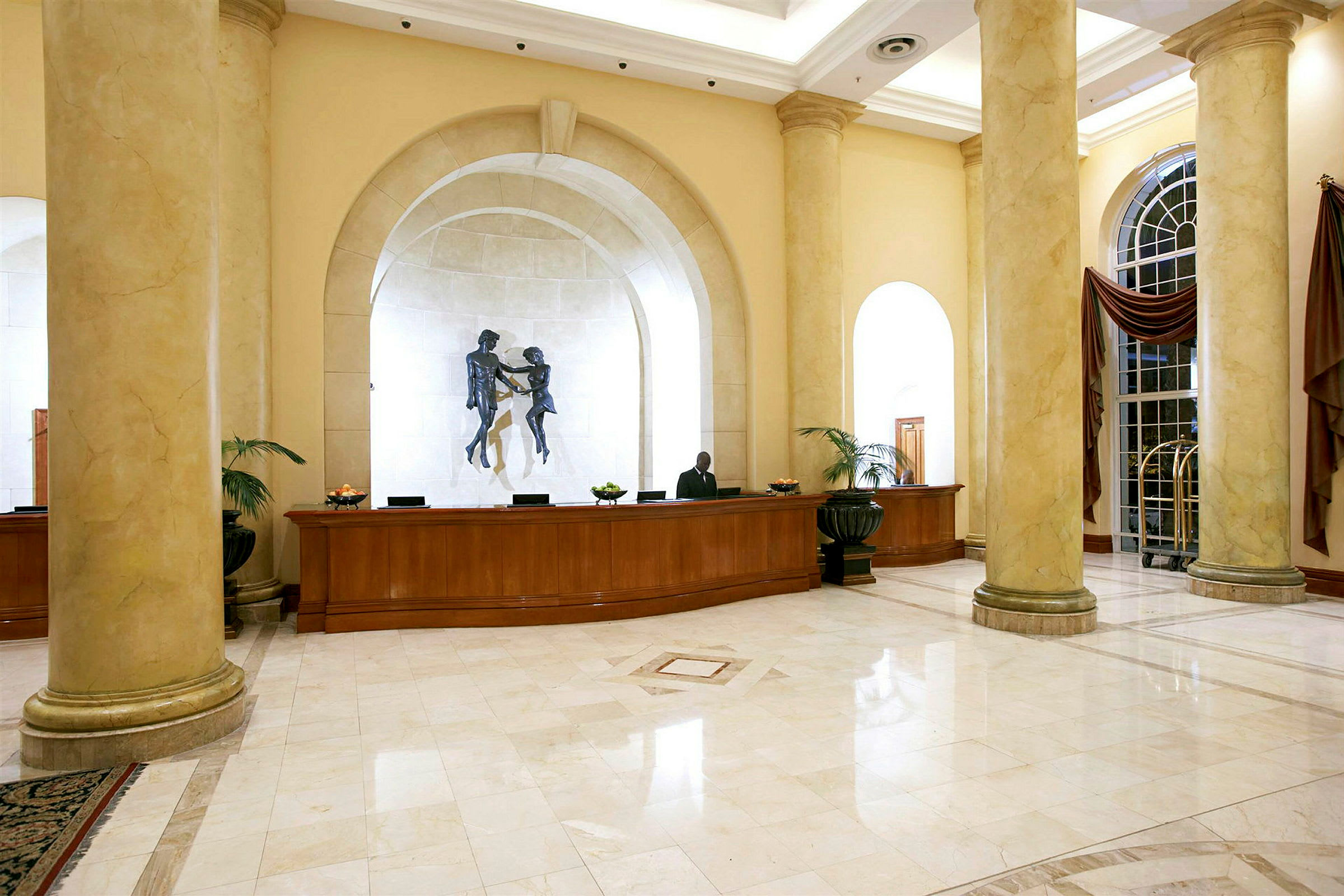 Hotellets lobby med reception, søjler og vægdekoration. (AI-genereret tekst)