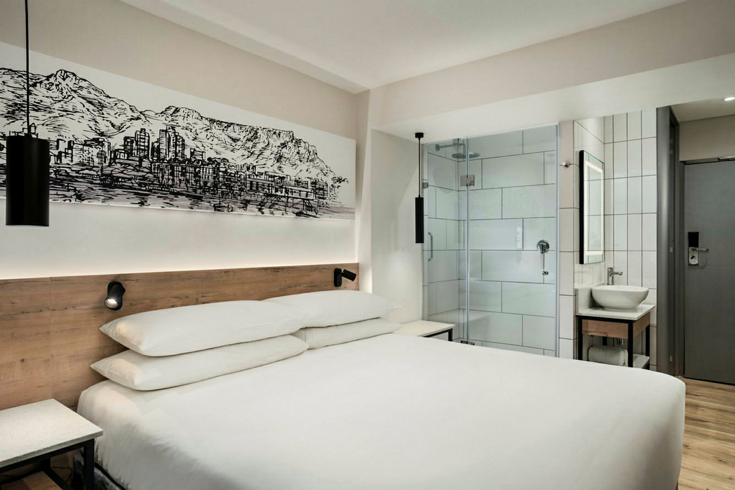 Moderne hotelværelse med en dobbeltseng, glasdør til badeværelset og vægkunst. (AI-genereret tekst)