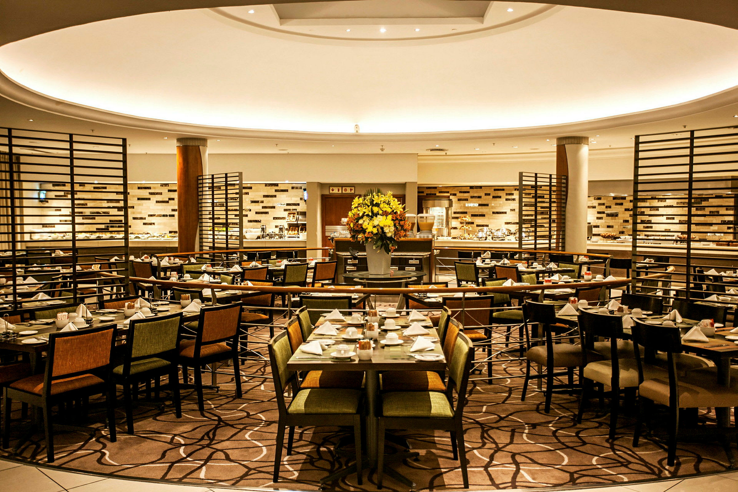 Et interiørbillede af en elegant restaurant med opdækkede borde og en stor blomsterbuket i midten. (AI-genereret tekst)