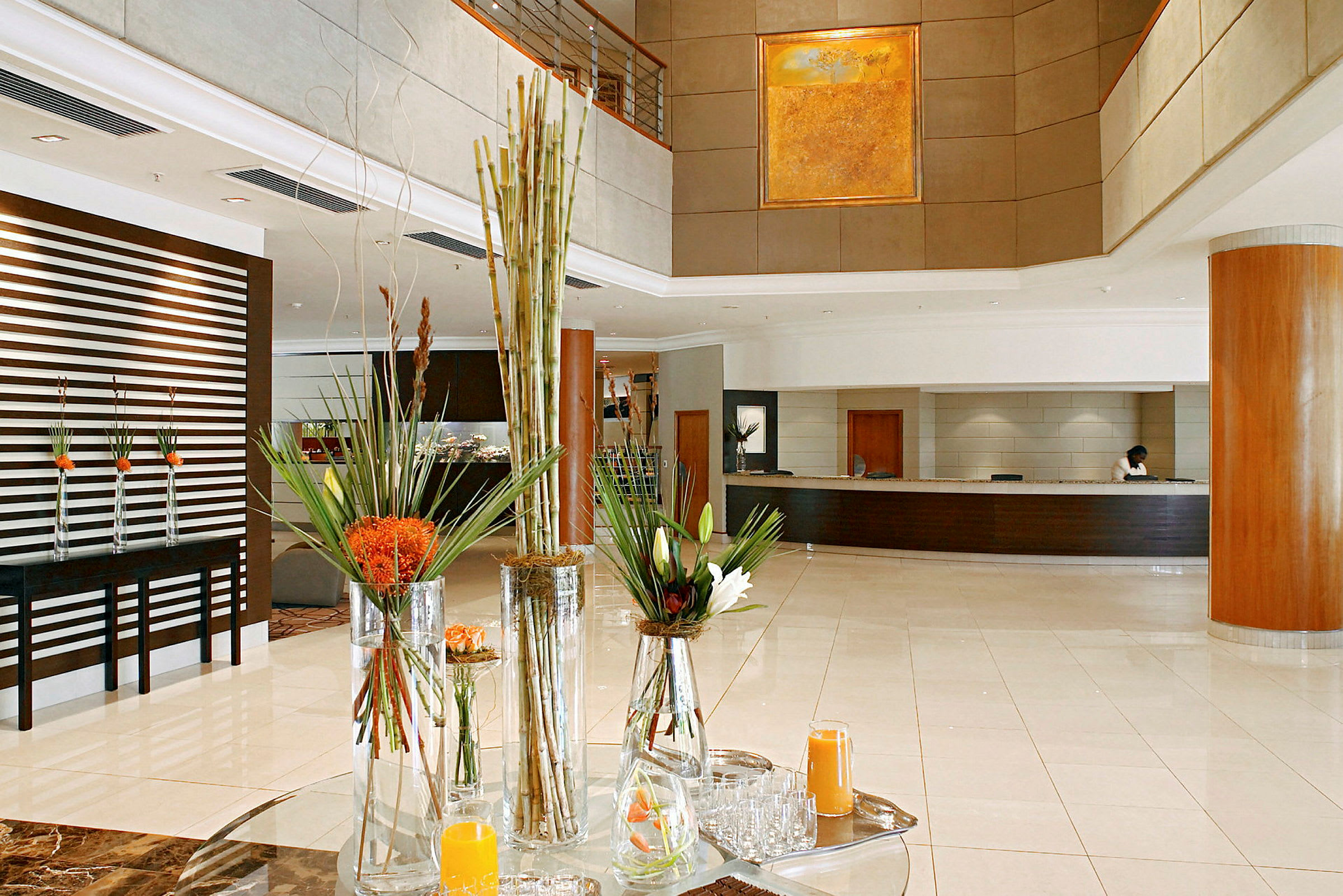 Lys og stilren hotellobby med reception og blomsterarrangement. (AI-genereret tekst)