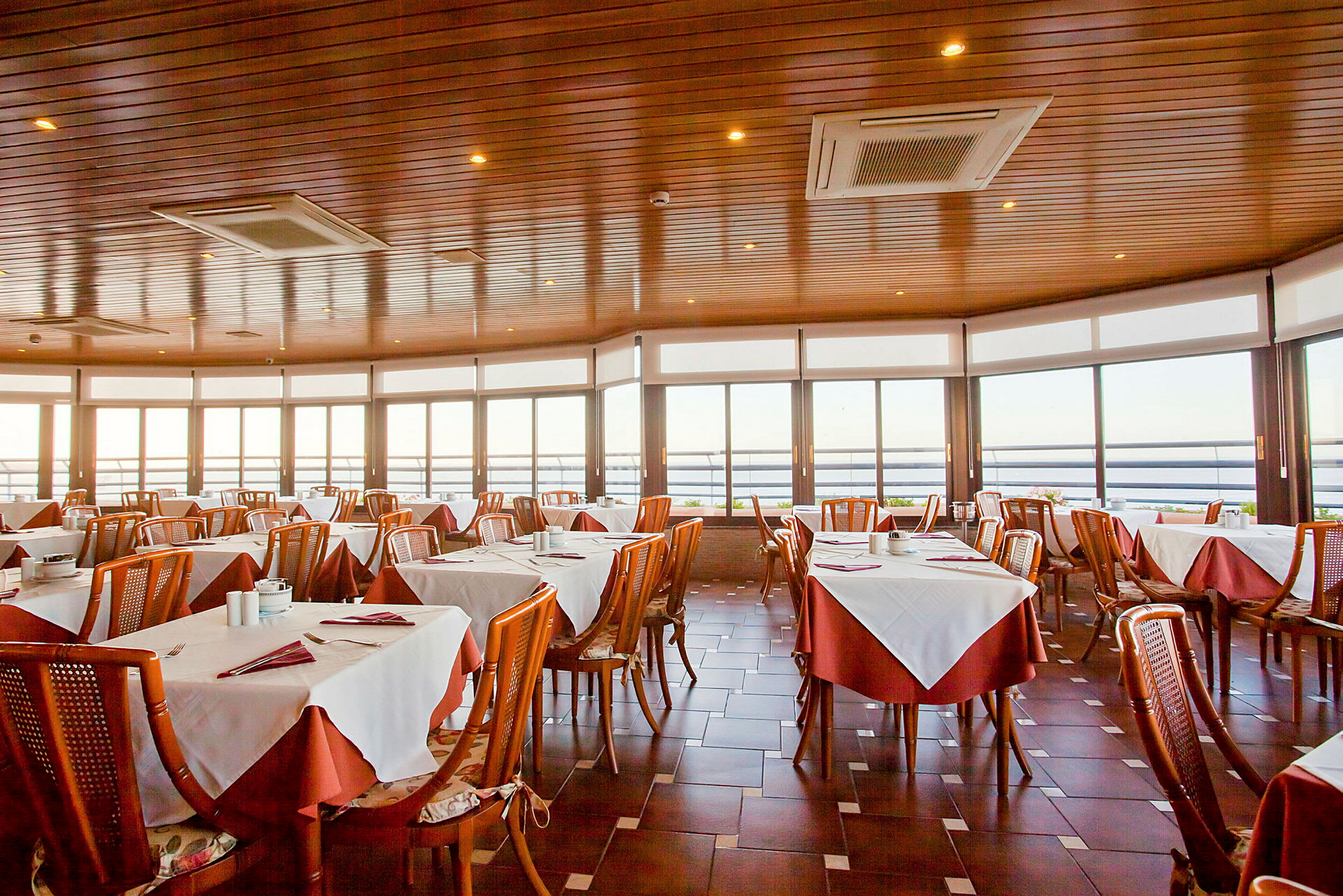 En restaurant med dækkede borde og store vinduer med udsigt. (AI-genereret tekst)