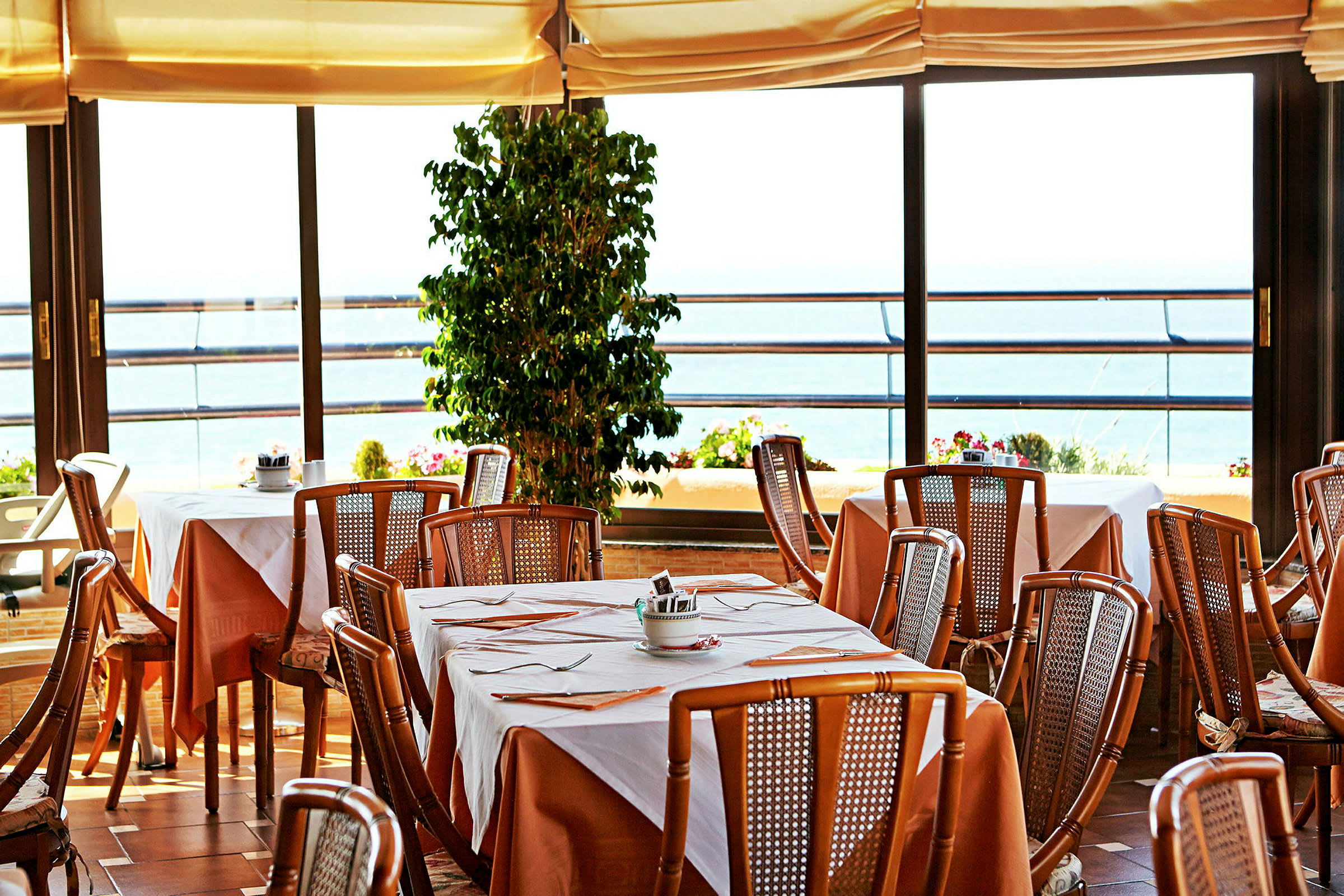 Restaurant med dækkede borde og udsigt mod havet. (AI-genereret tekst)