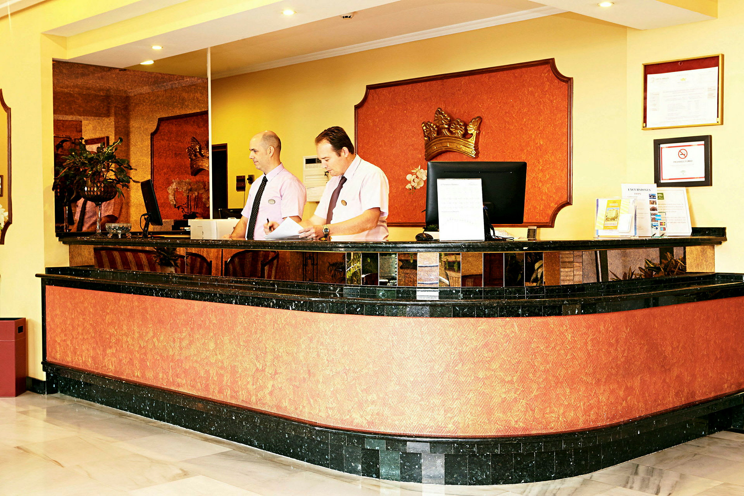 Reception i en hotellobby med sort og orange farvevalg og dekorationer. (AI-genereret tekst)