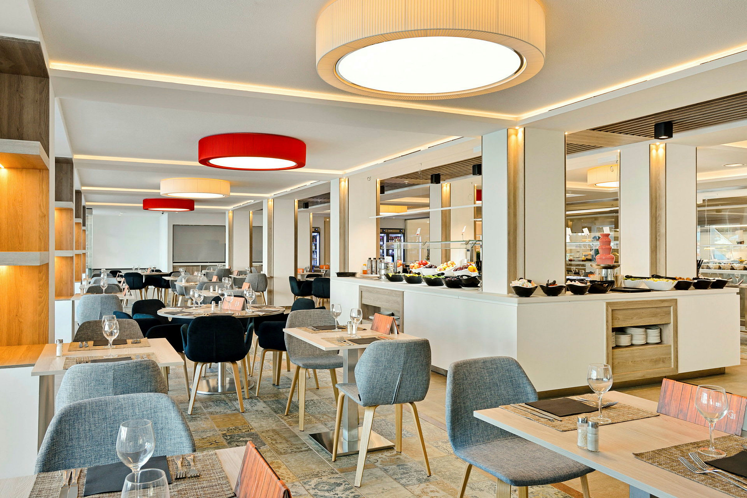 Et lyst interiør af en spisestue med borde og stole samt en buffet i baggrunden. (AI-genereret tekst)