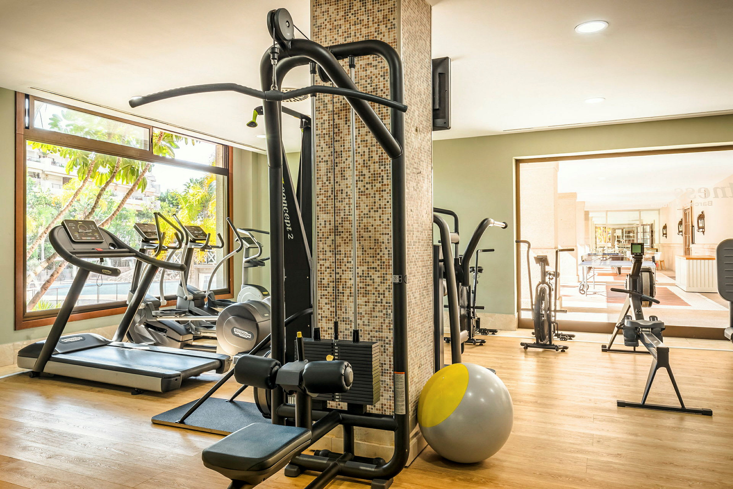 Et moderne fitnesscenter med træningsudstyr, herunder løbebånd, styrketræningsmaskiner og pilatesbold. (AI-genereret tekst)