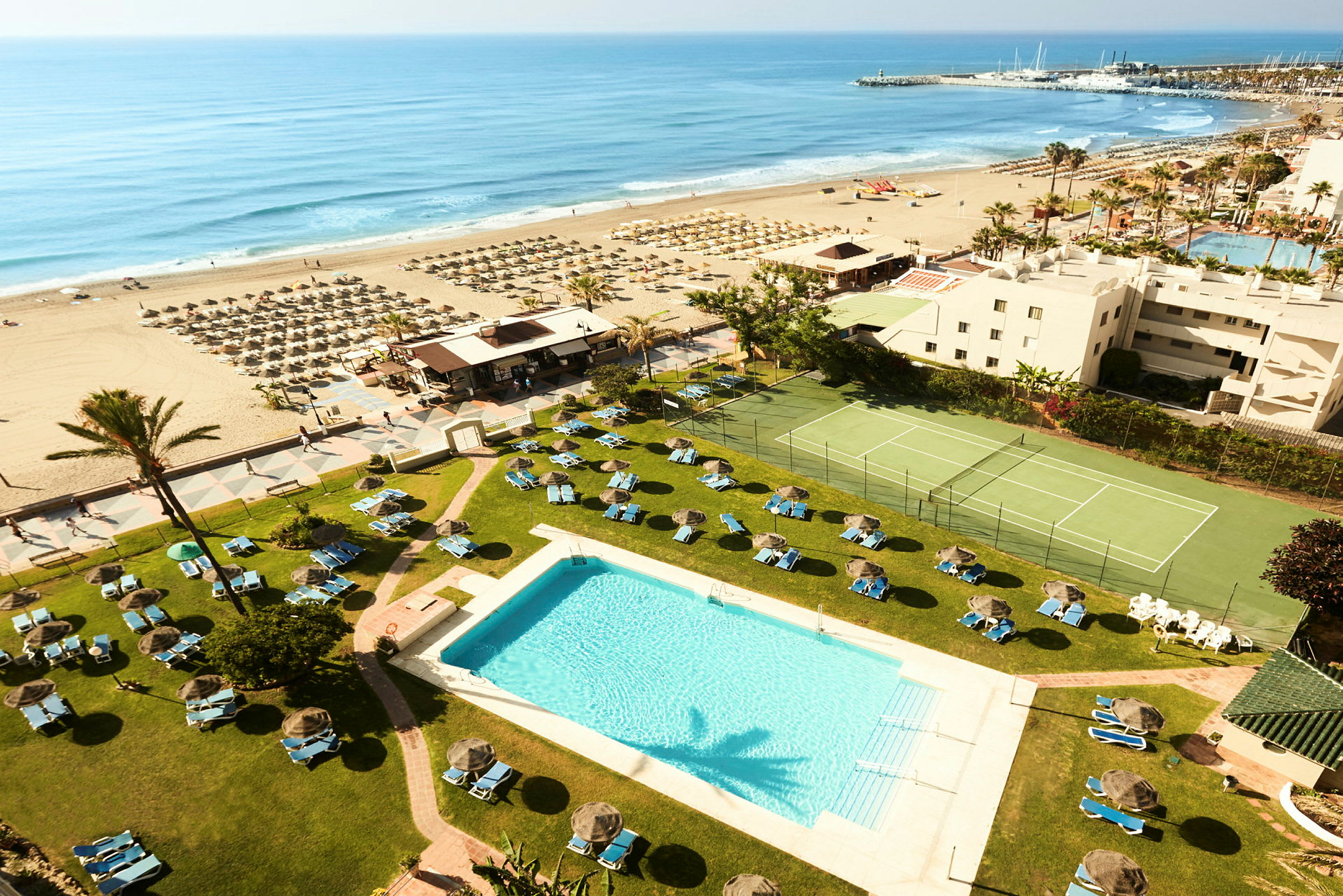 Hotellets poolområde med udsigt over stranden og havet. (AI-genereret tekst)
