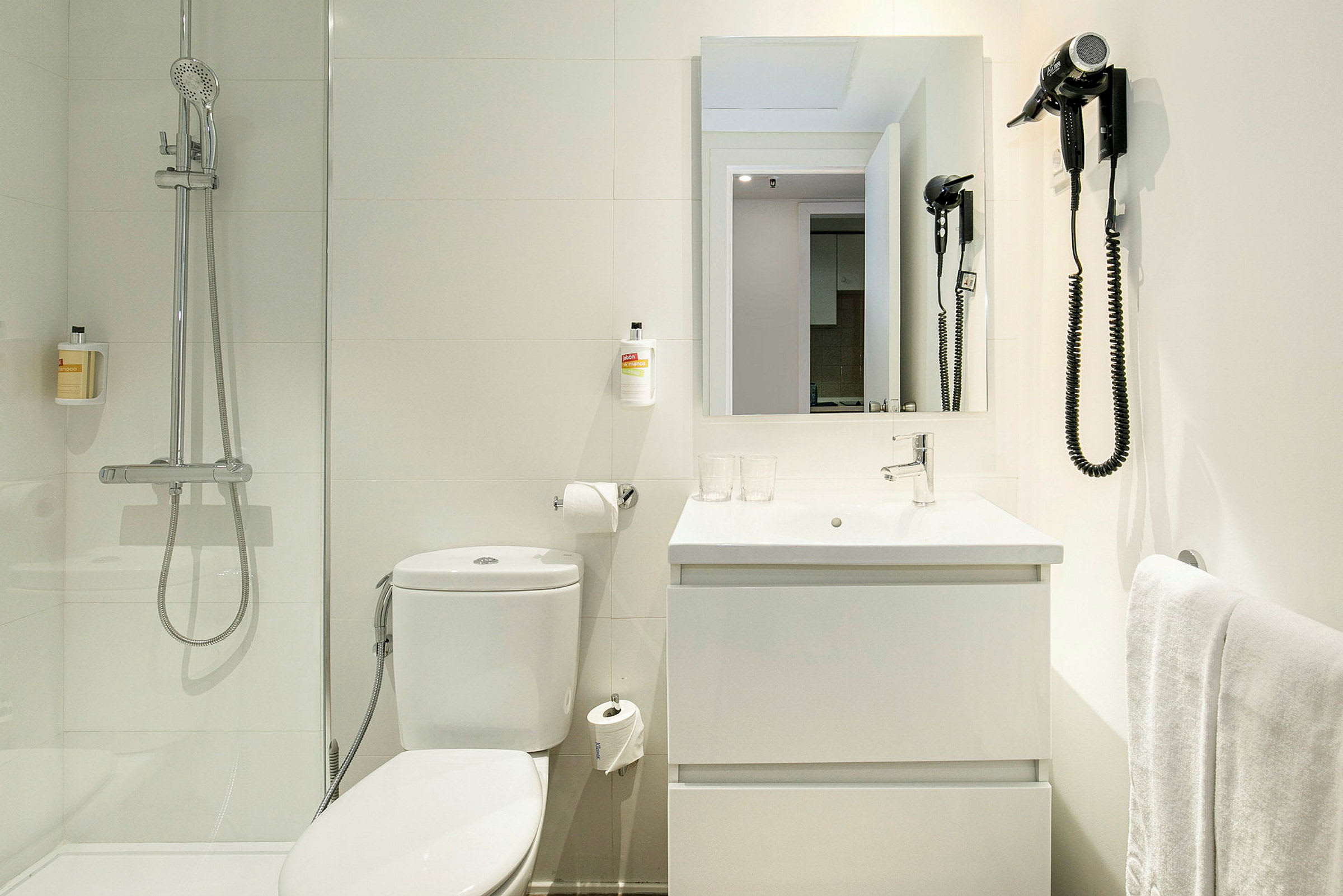 Et badeværelse med en bruser, toilet, håndvask og spejl. (AI-genereret tekst)
