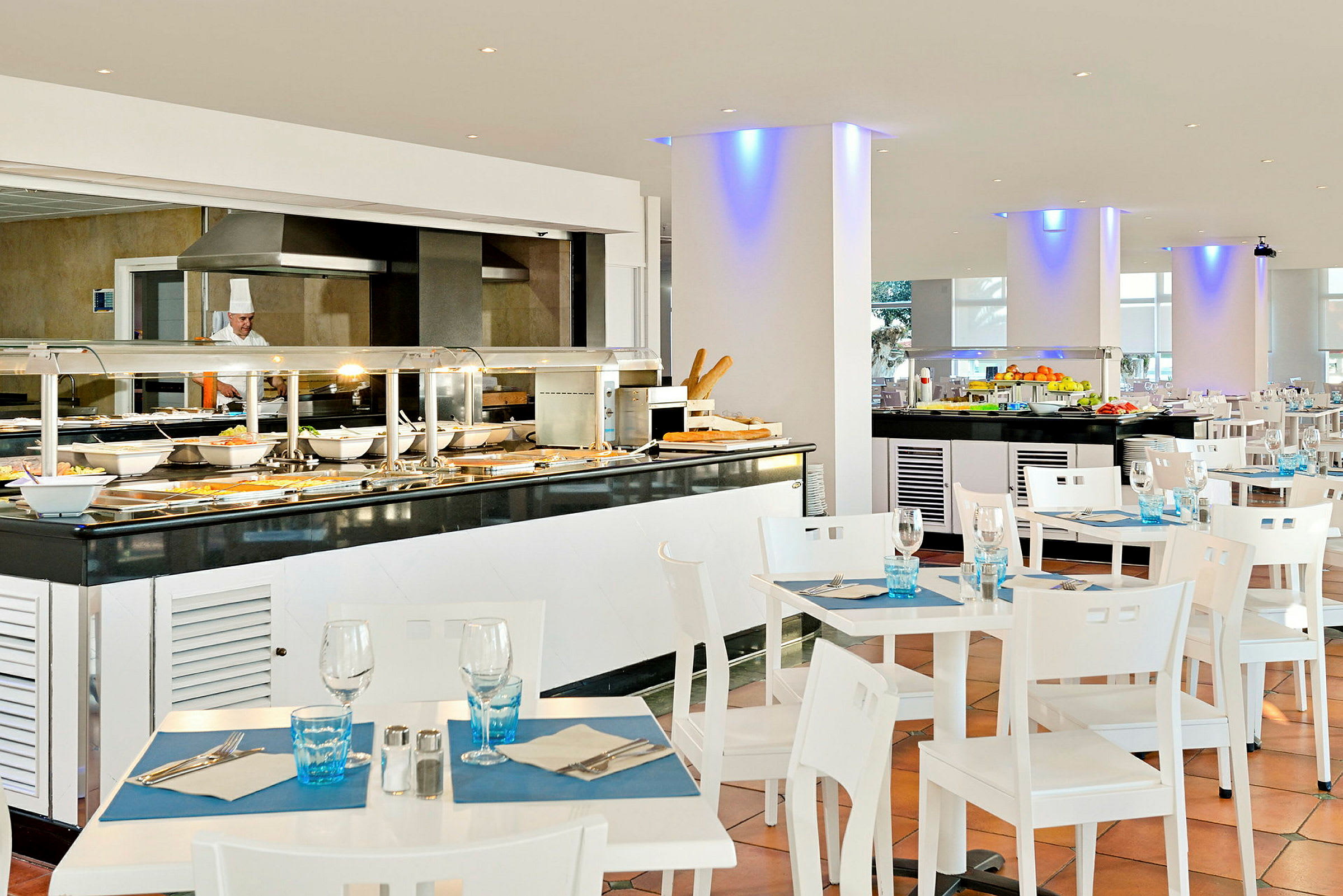 En lys og moderne buffetrestaurant med dækkede borde og forskellige serveringsstationer. (AI-genereret tekst)