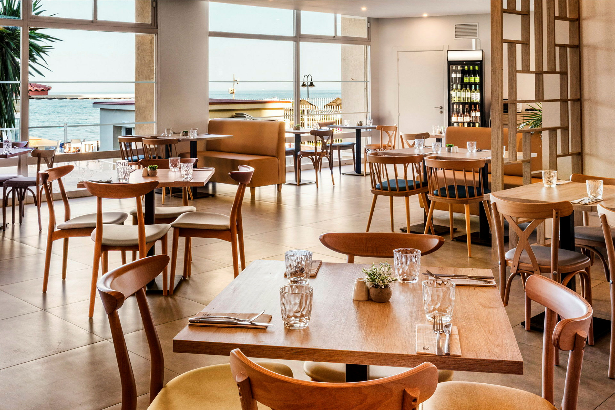 Moderne borde og stole i træ i en restaurant med havudsigt. (AI-genereret tekst)