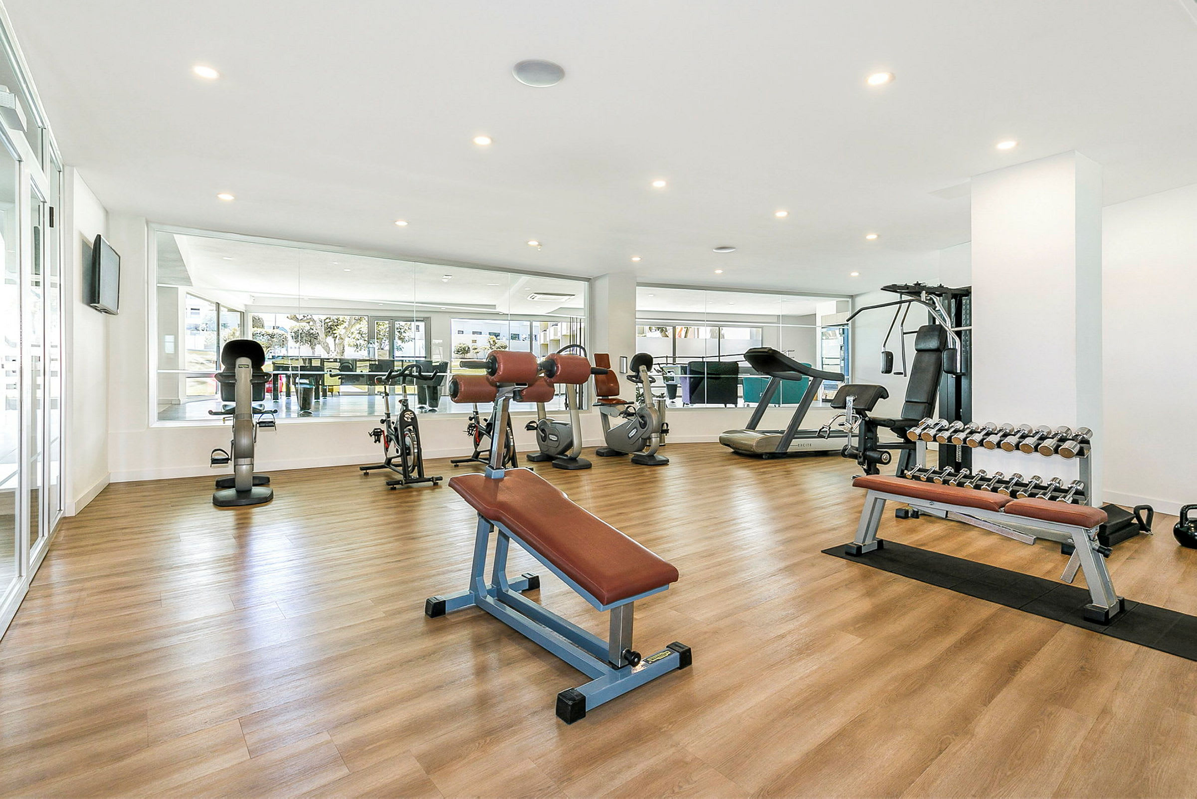 Et fitnesscenter med styrketræningsmaskiner, løbebånd, cykler og håndvægte. (AI-genereret tekst)