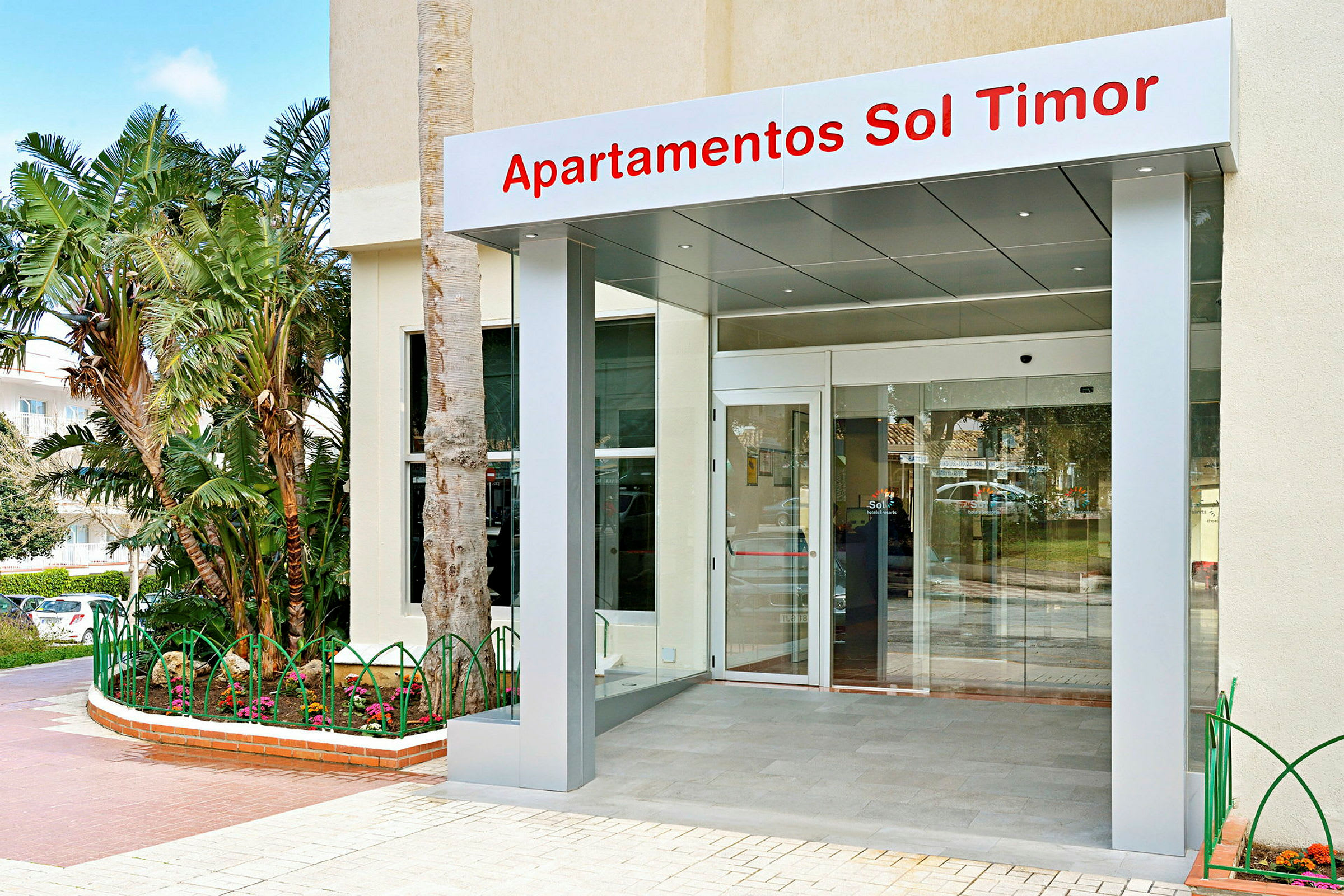 Indgangen til Sol Timor Apartments med glasdør og skilt. (AI-genereret tekst)