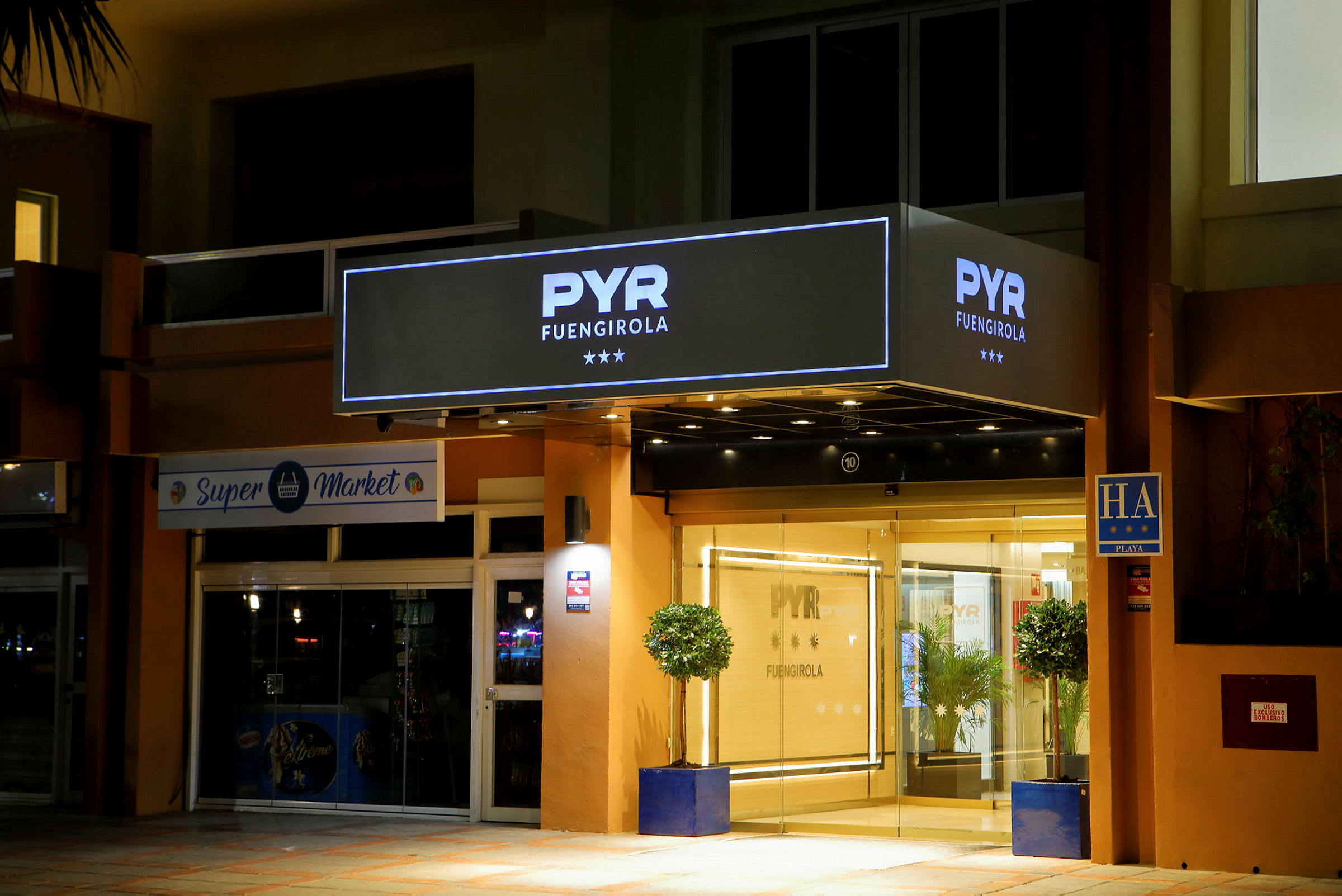 Hotelindgangen til PYR Fuengirola med belysning og skilte. (AI-genereret tekst)