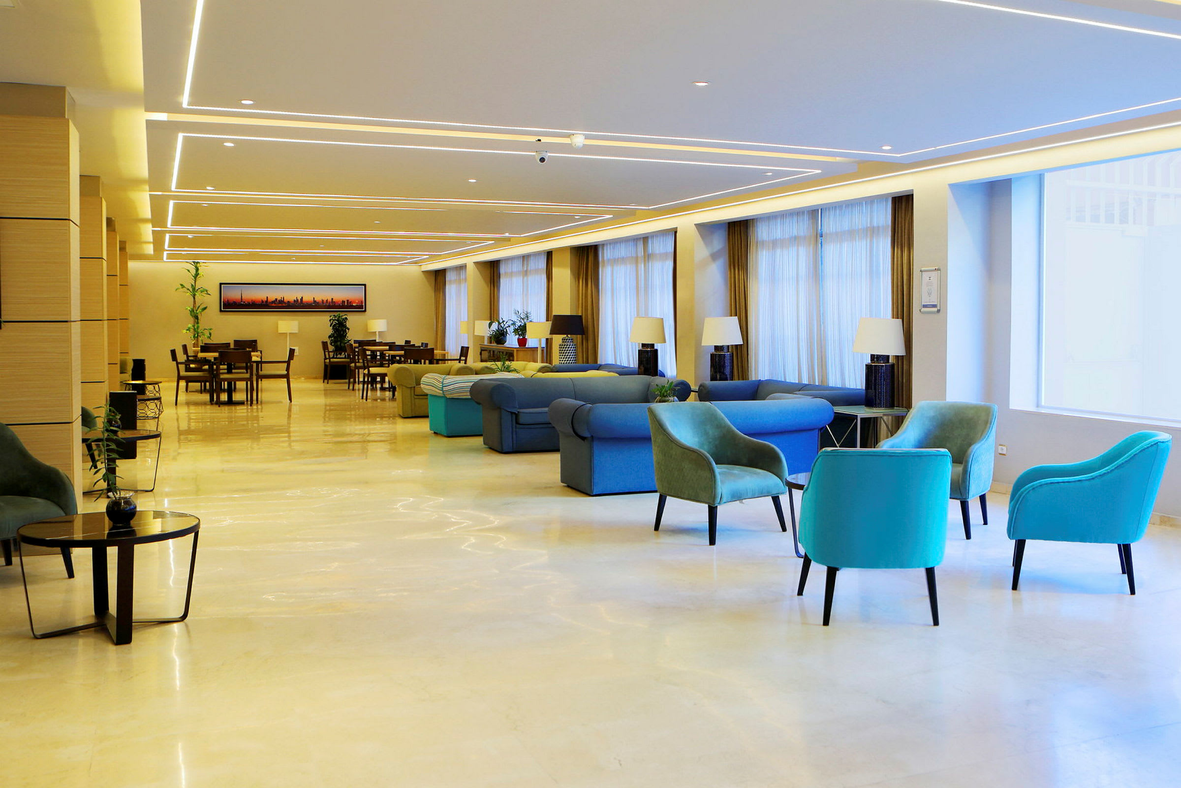 En rummelig hotellobby med forskellige siddepladser og borde, dekoreret med lamper og planter. (AI-genereret tekst)