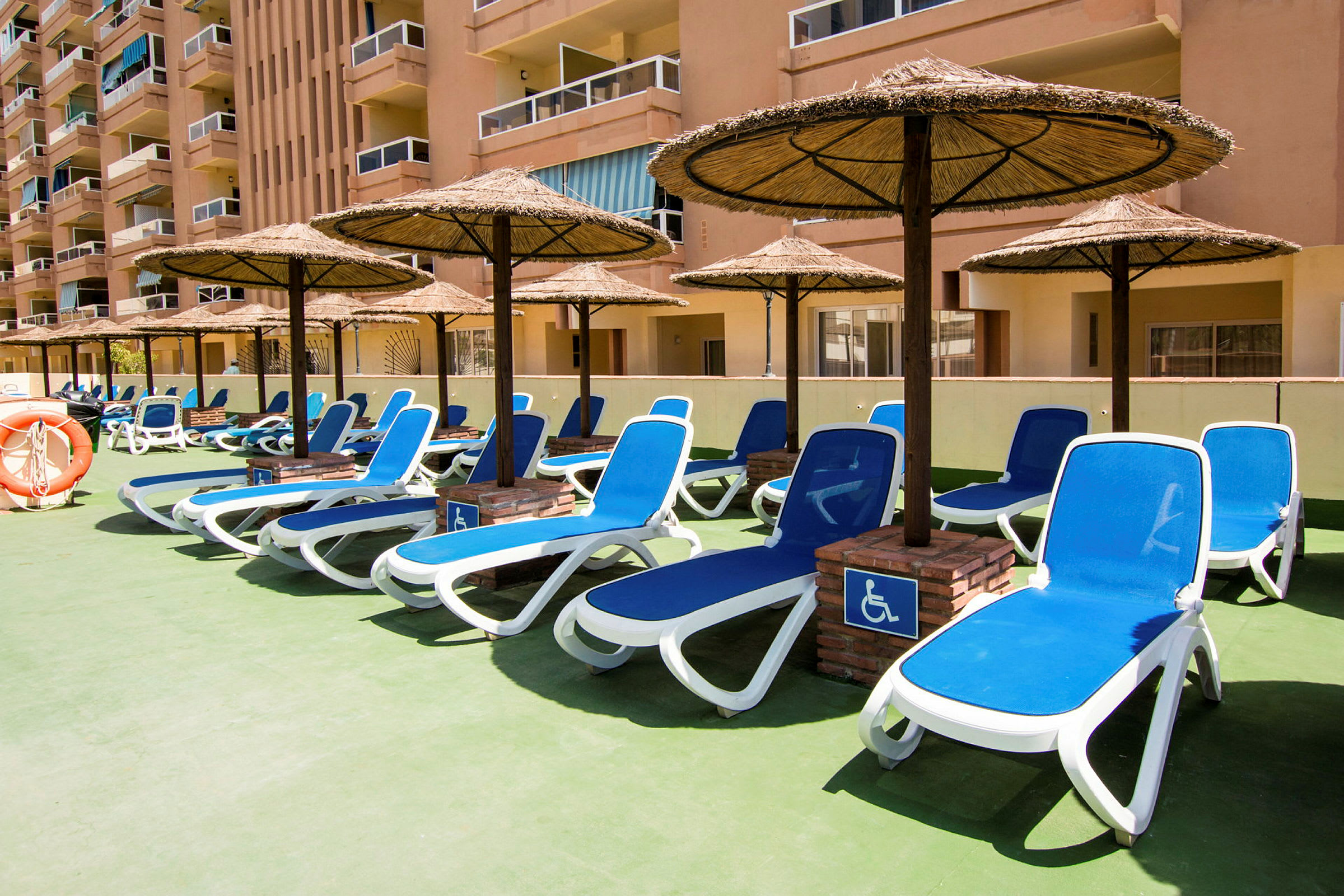 Solsenge med parasoller på en hotelterrasse. (AI-genereret tekst)