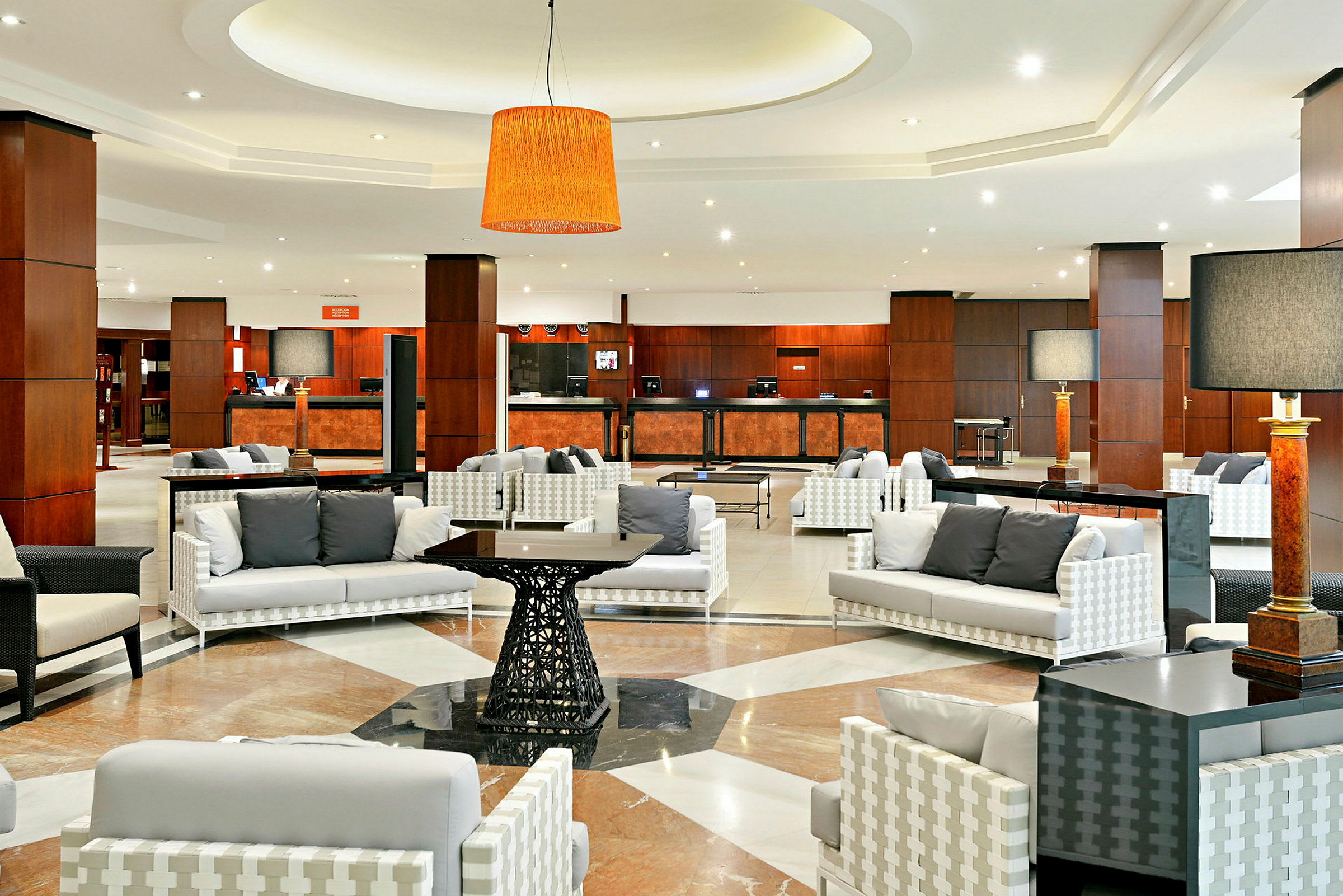 Et moderne hotellobbyområde med siddegrupper og reception i baggrunden. (AI-genereret tekst)