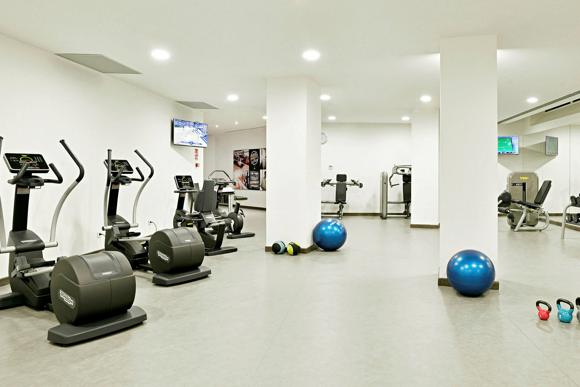 Et fitnessrum med træningsmaskiner, træningsbolde og kettlebells. (AI-genereret tekst)