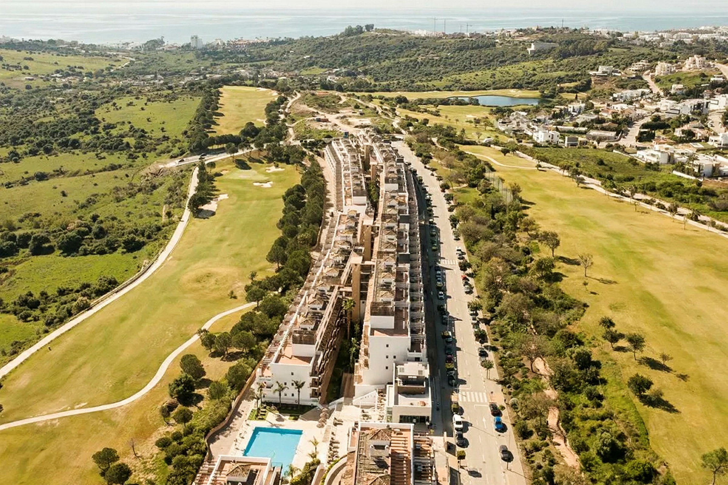 Luftfoto af et boligkompleks med pool, ved siden af en golfbane og grønt landskab. (AI-genereret tekst)
