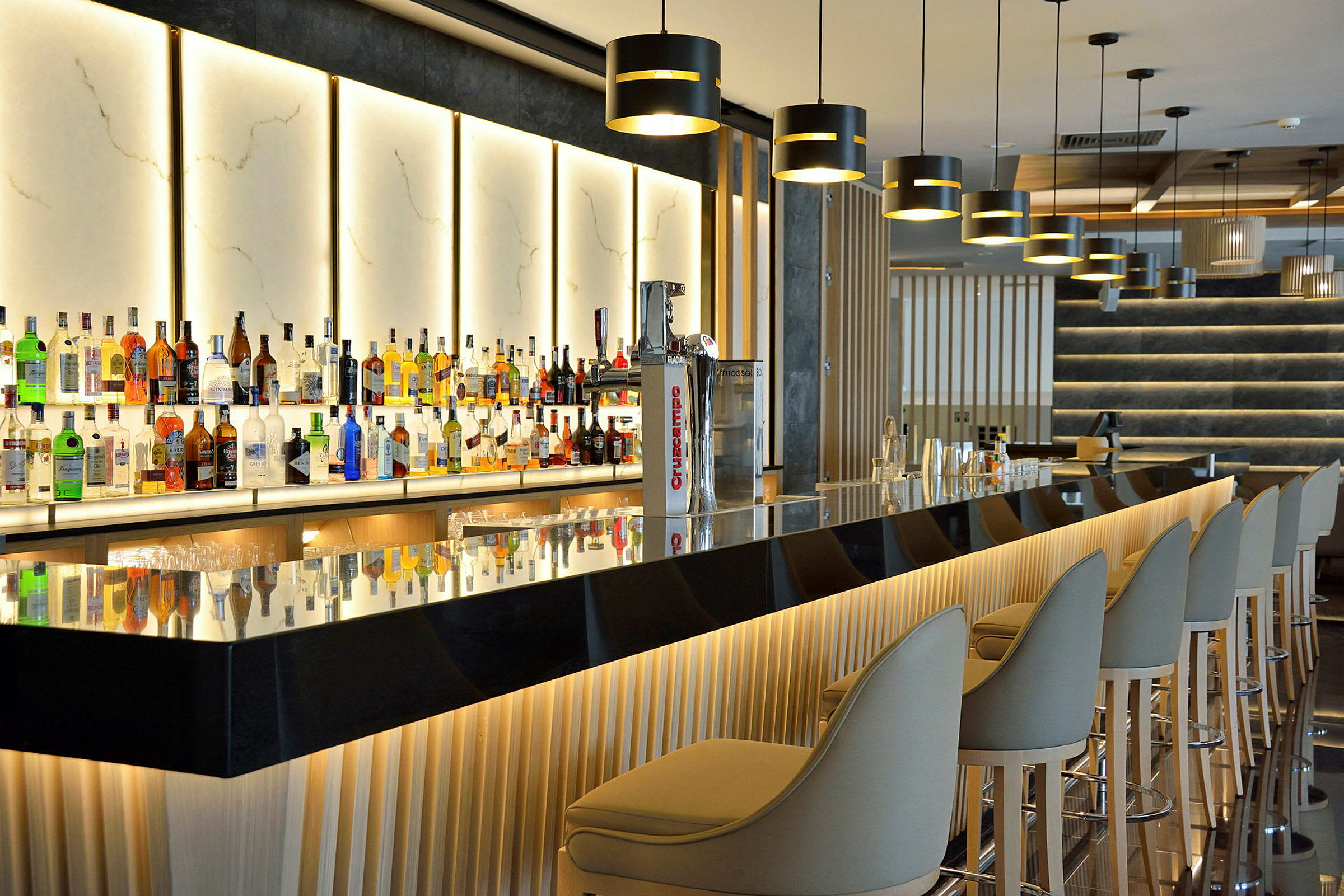 En moderne bar med belyste flaskereoler og elegante siddepladser. (AI-genereret tekst)