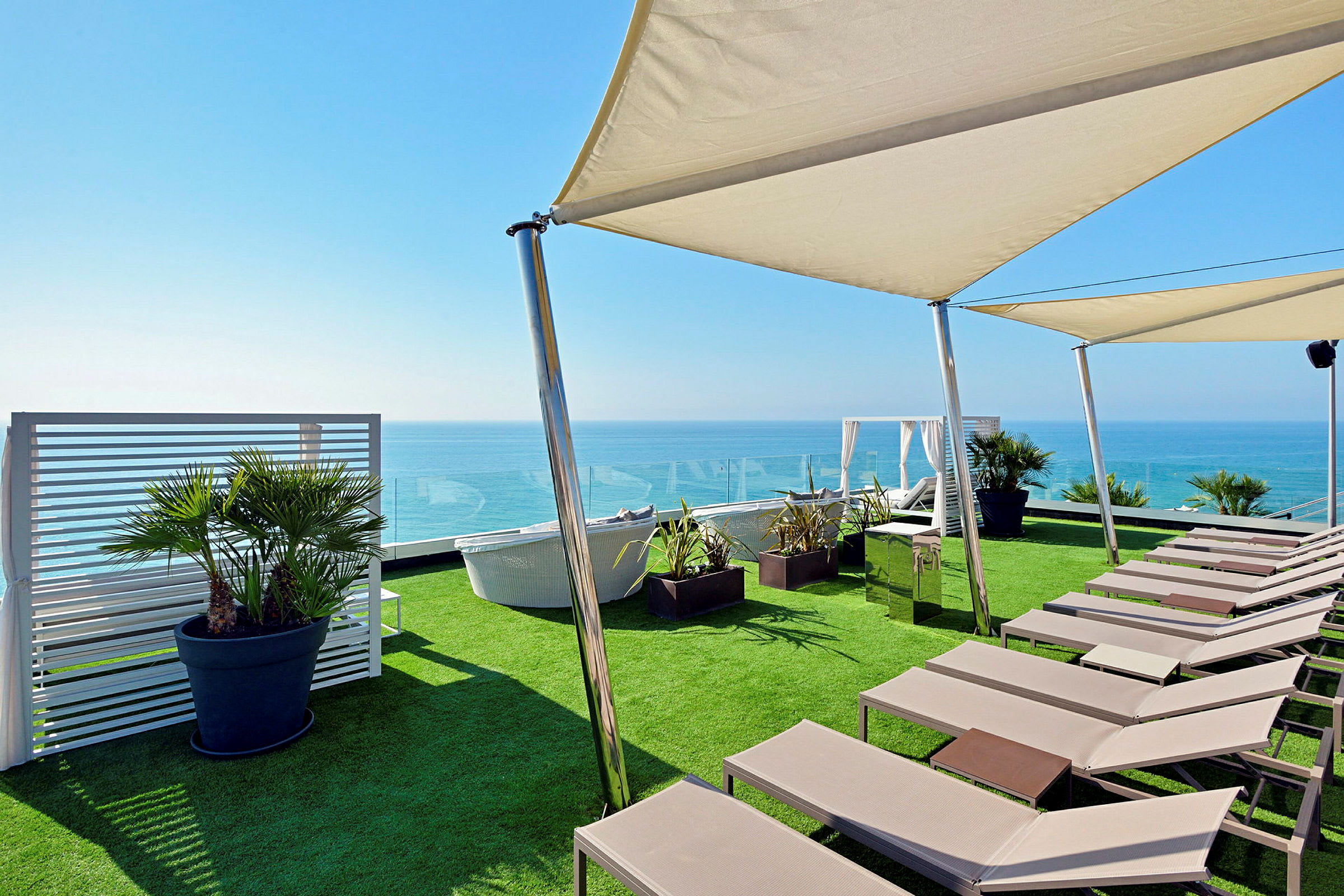 Liggestole og parasoller på en terrasse med udsigt over havet. (AI-genereret tekst)