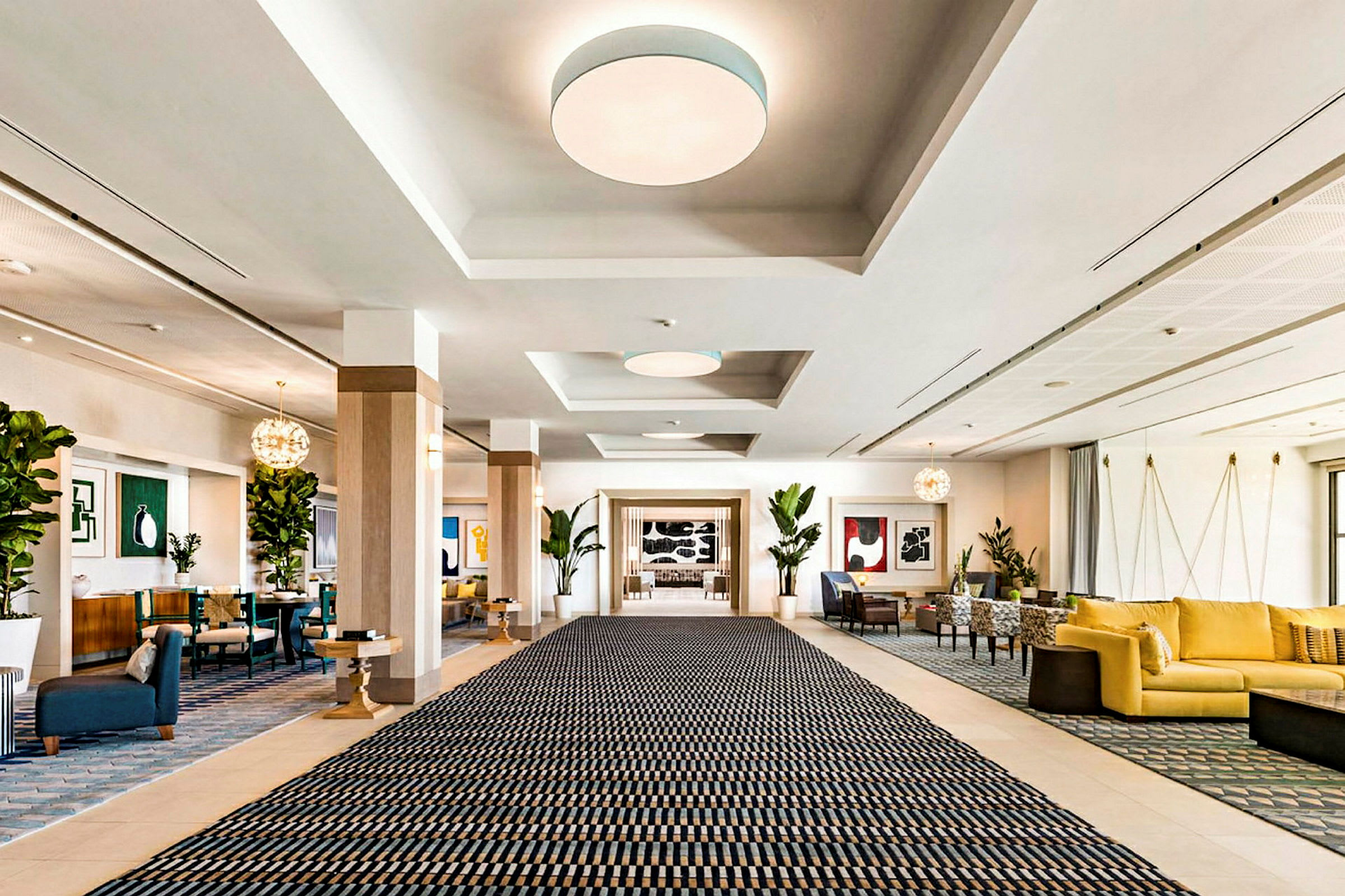 En rummelig hotellobby med et stort tæppe, siddeområder og dekorationer. (AI-genereret tekst)