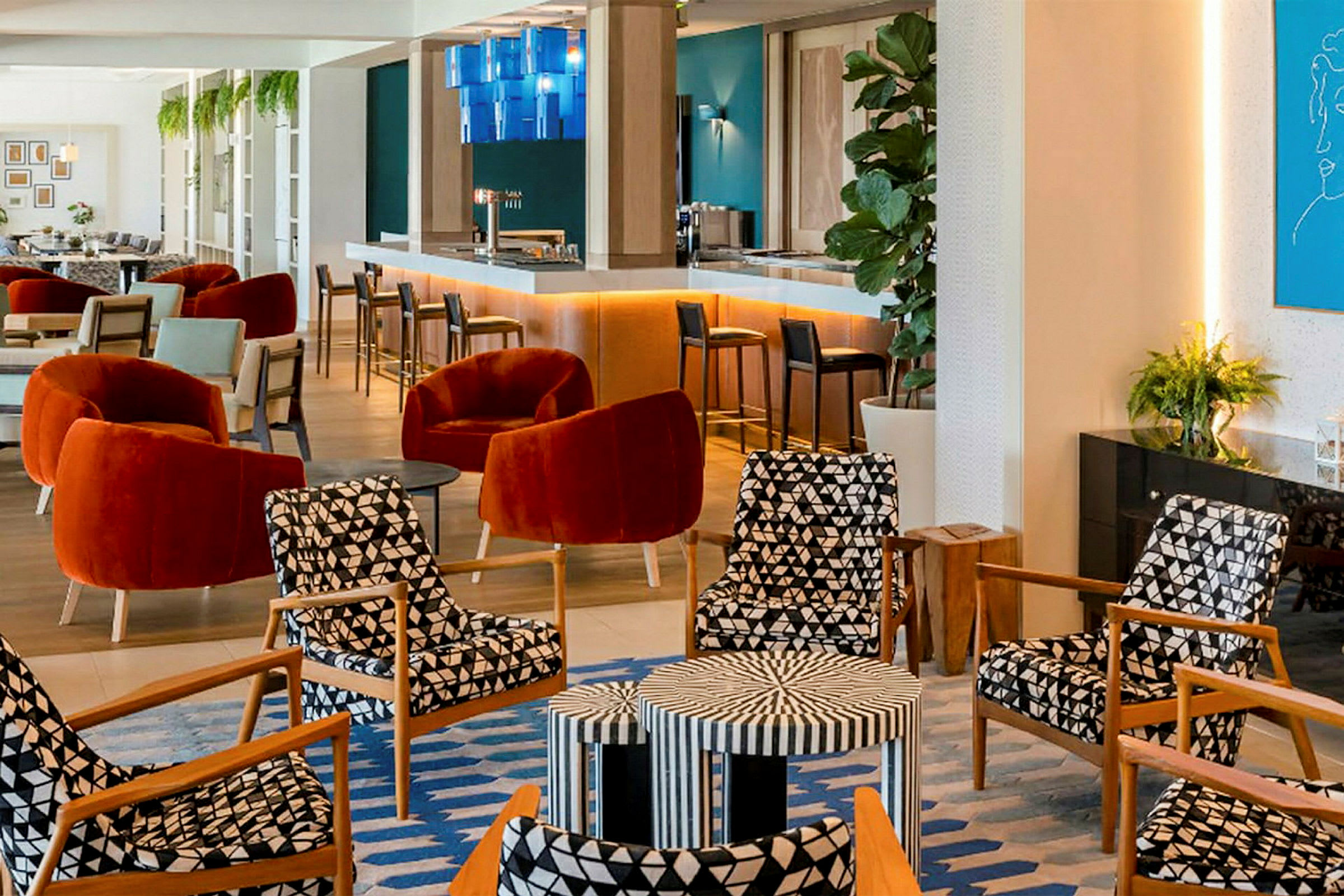 En moderne lounge med komfortable stole i røde og mønstrede farver, et barområde og vægdekorationer. (AI-genereret tekst)