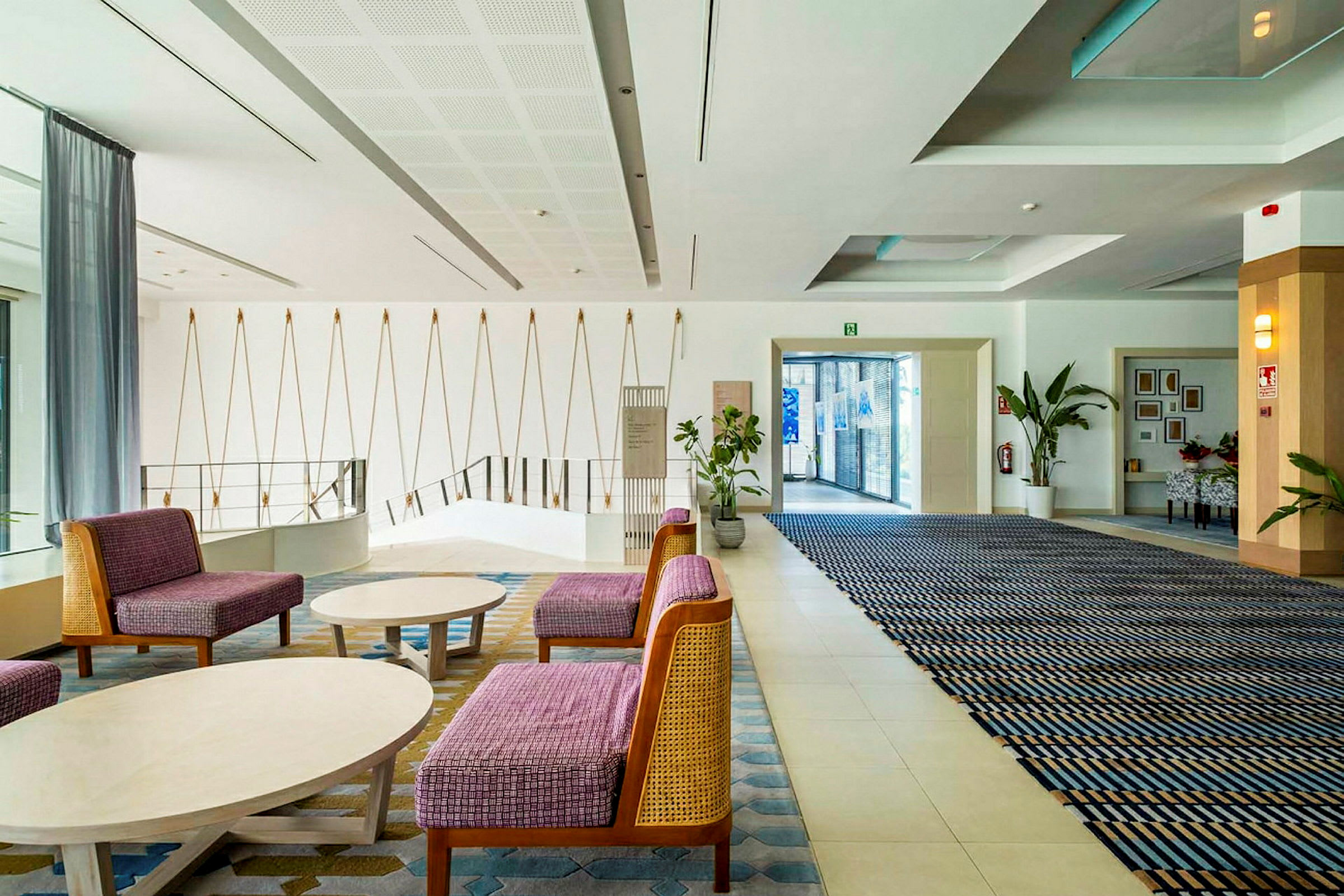 Et moderne hotellets loungeområde med siddepladser, vægdekorationer og plantearrangementer. (AI-genereret tekst)