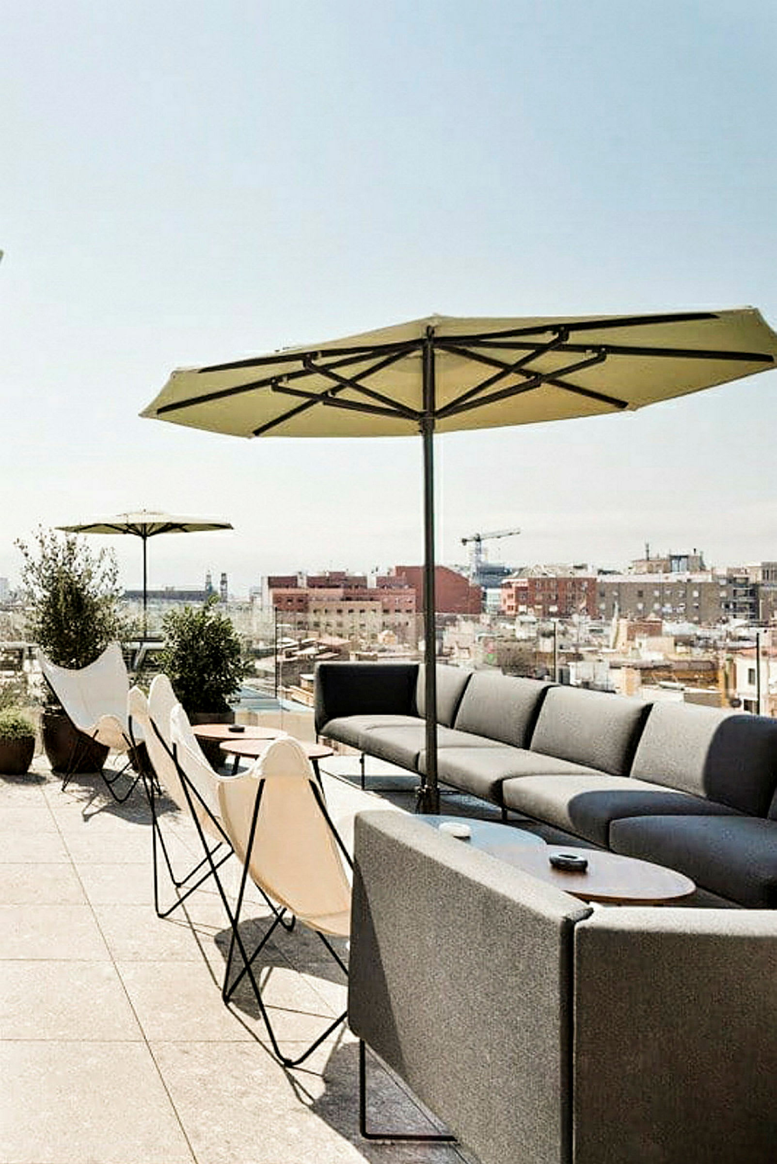 Billede af en terrasse med siddepladser, parasoller og udsigt over byens tage. (AI-genereret tekst)
