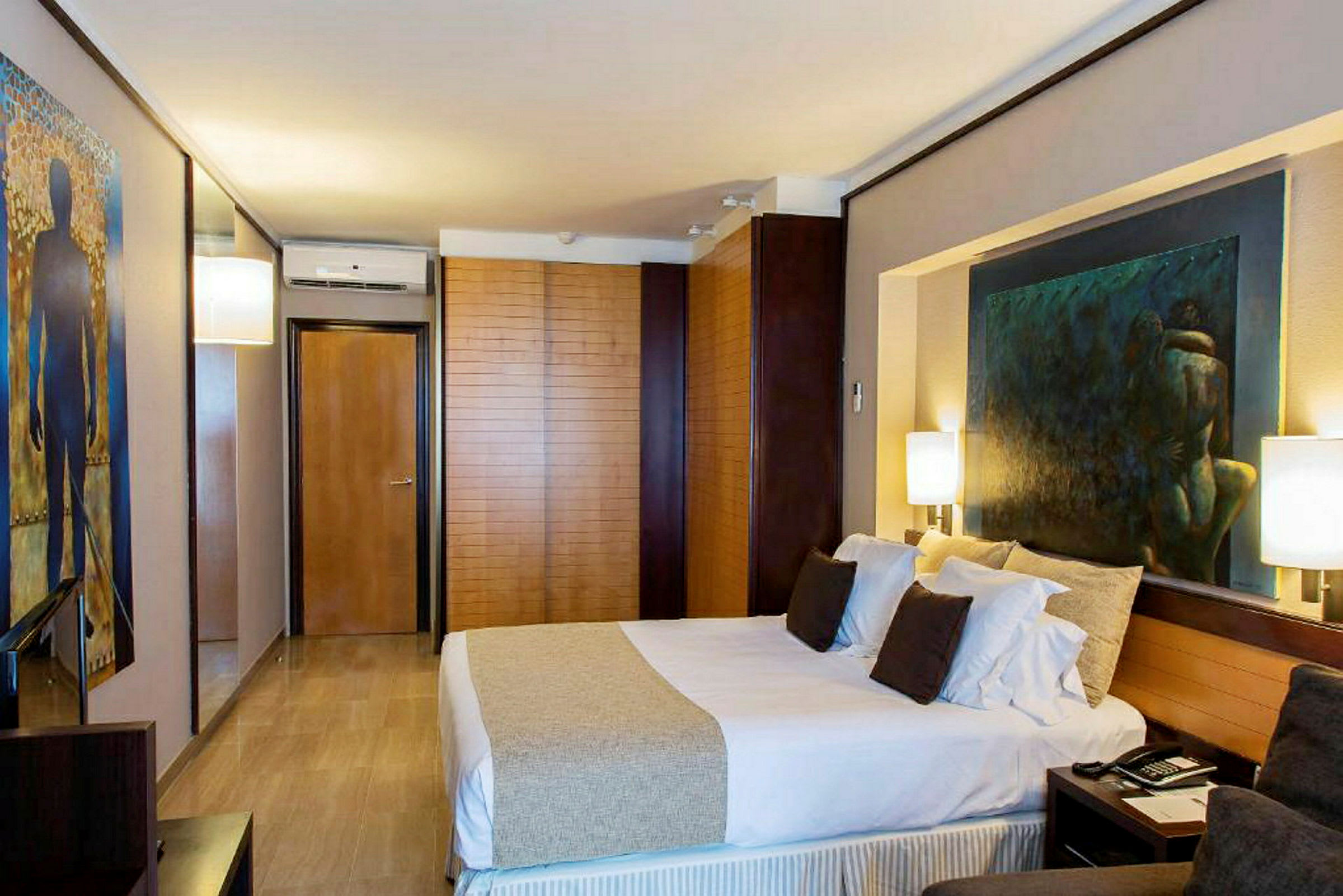 Et moderne hotelværelse med en dobbeltseng, malerier på væggene og elegant indretning. (AI-genereret tekst)