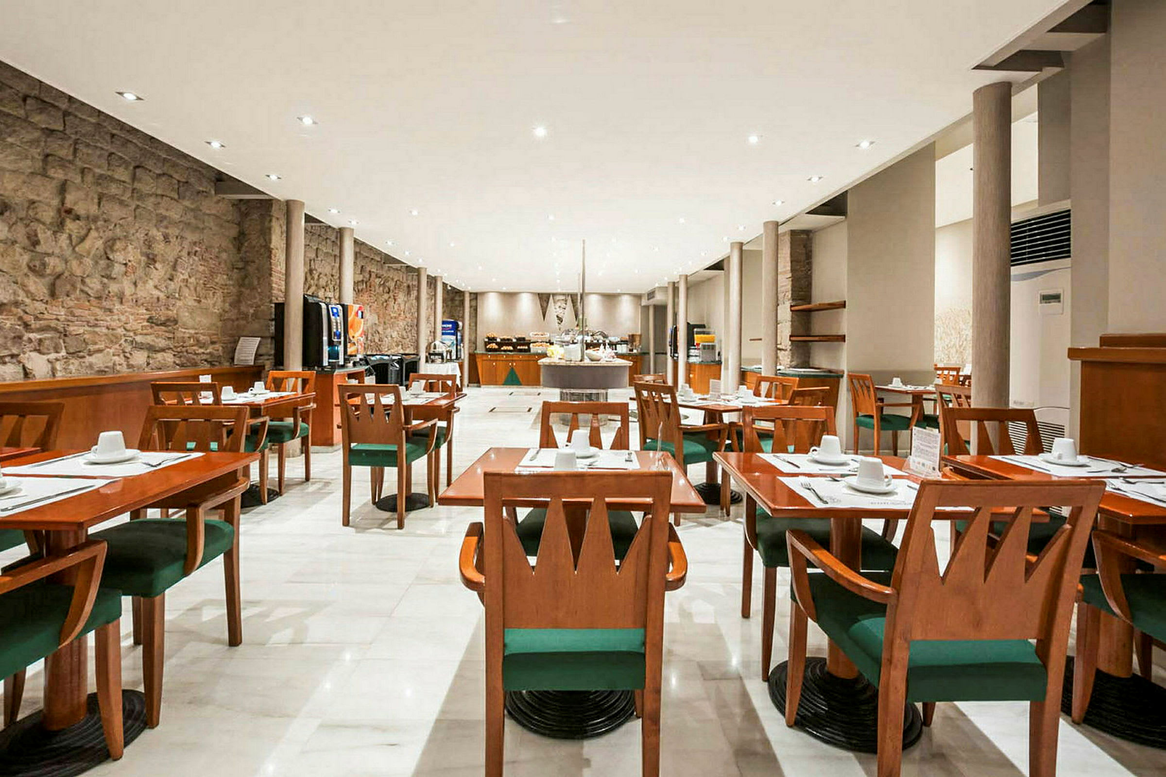 Et rummeligt restaurantområde med træmøbler, hvide duge, grønne stole og en moderne indretning. (AI-genereret tekst)