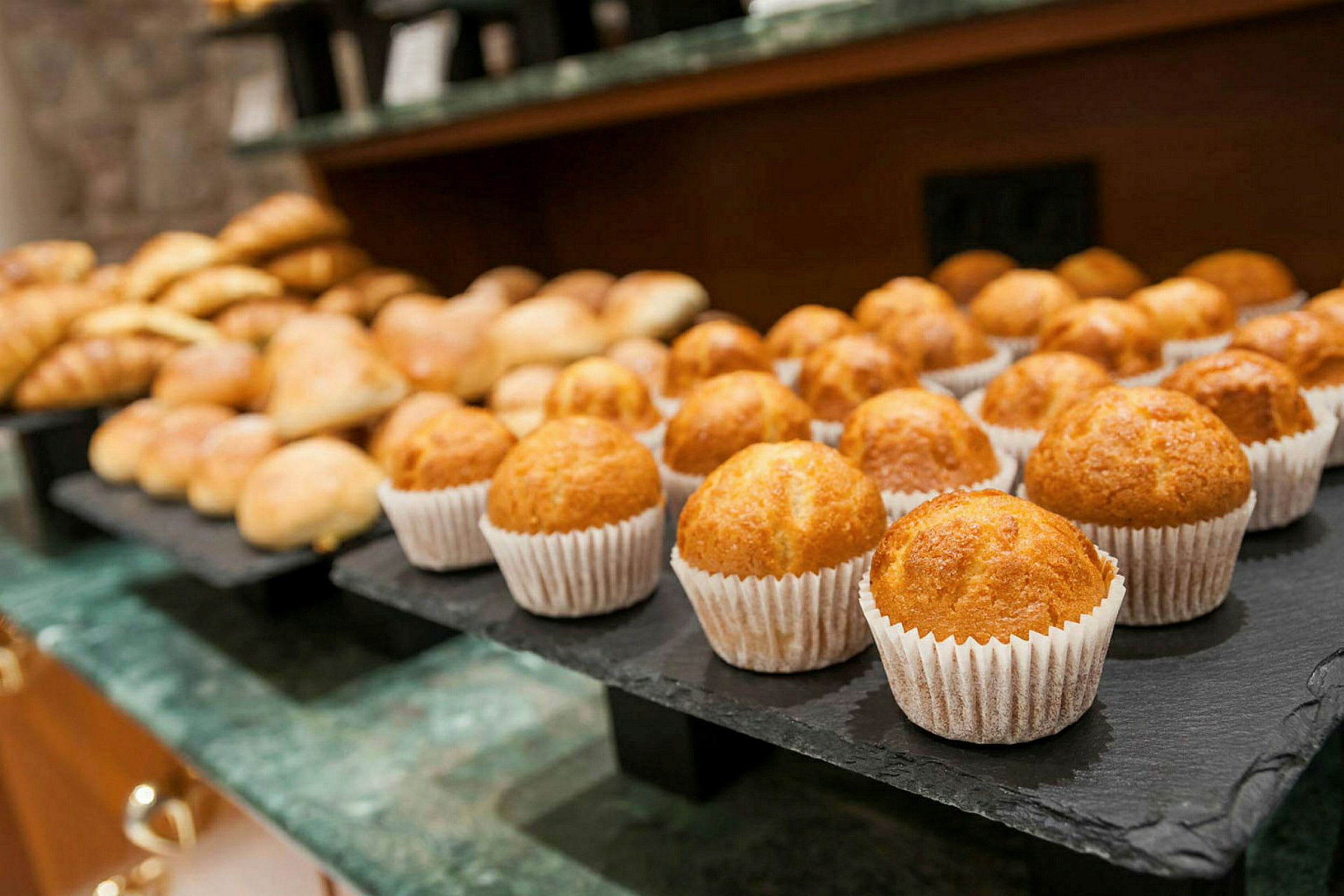 Et nærbillede af et fad med muffins og andre bagværk på et bord. (AI-genereret tekst)