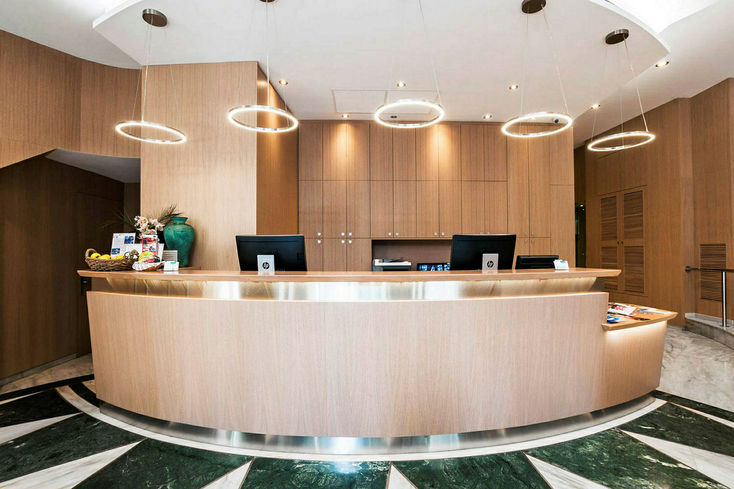 En receptionsdisk i træ med moderne lamper hængende over og et elegant design. (AI-genereret tekst)