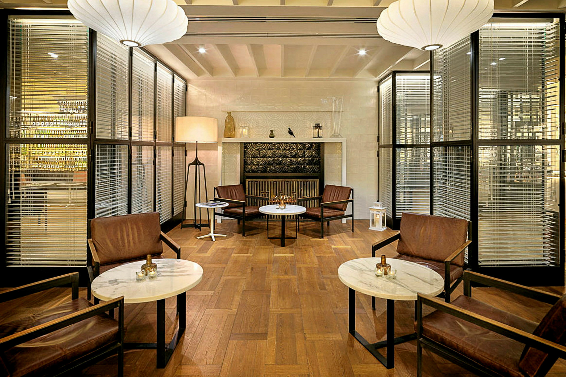 En elegant lounge med stole og runde borde på et trægulv, indrettet med lanterner og belysning. (AI-genereret tekst)