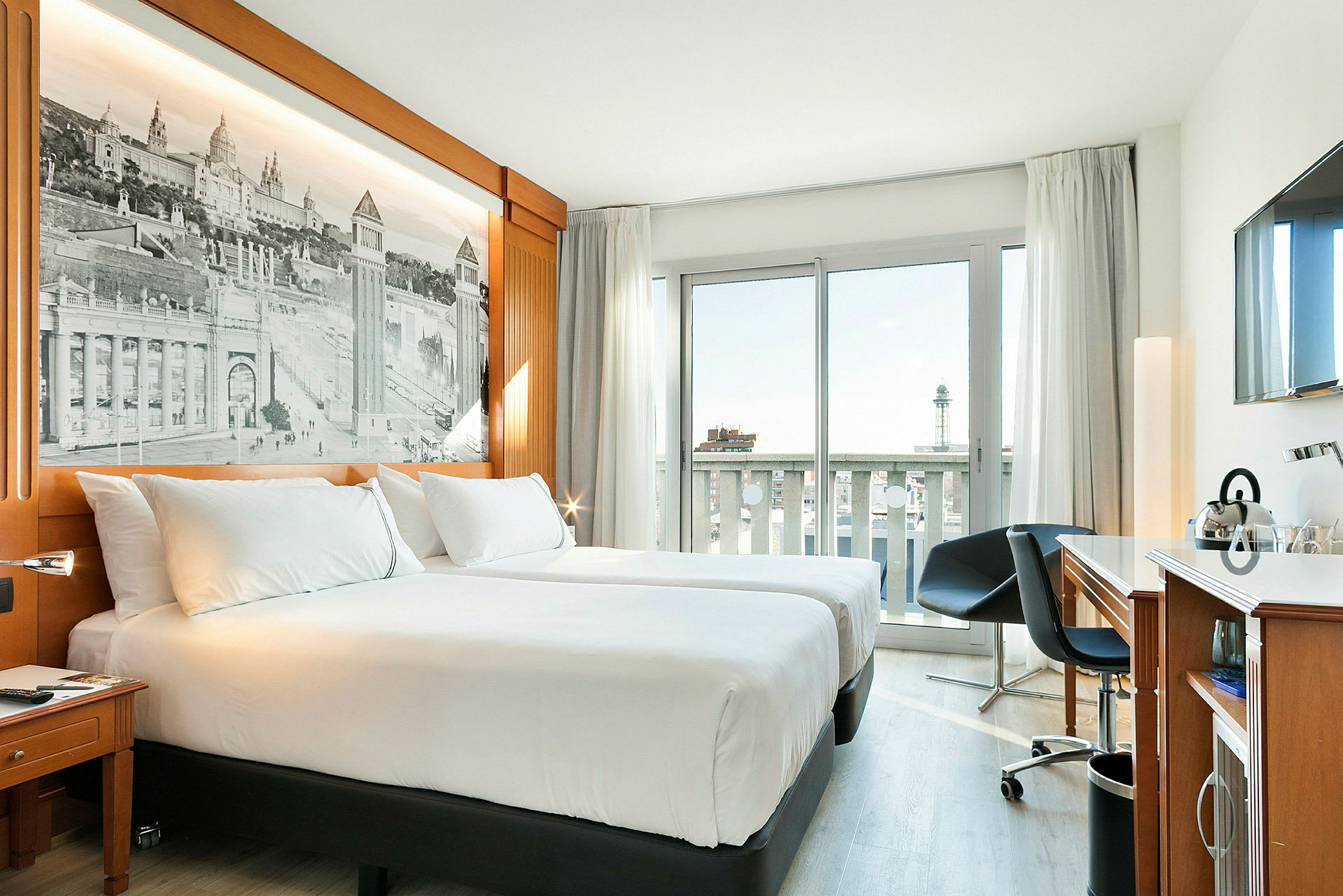 Hotelværelse med to enkeltsenge, et arbejdsområde og et vindue med balkonudsigt. (AI-genereret tekst)