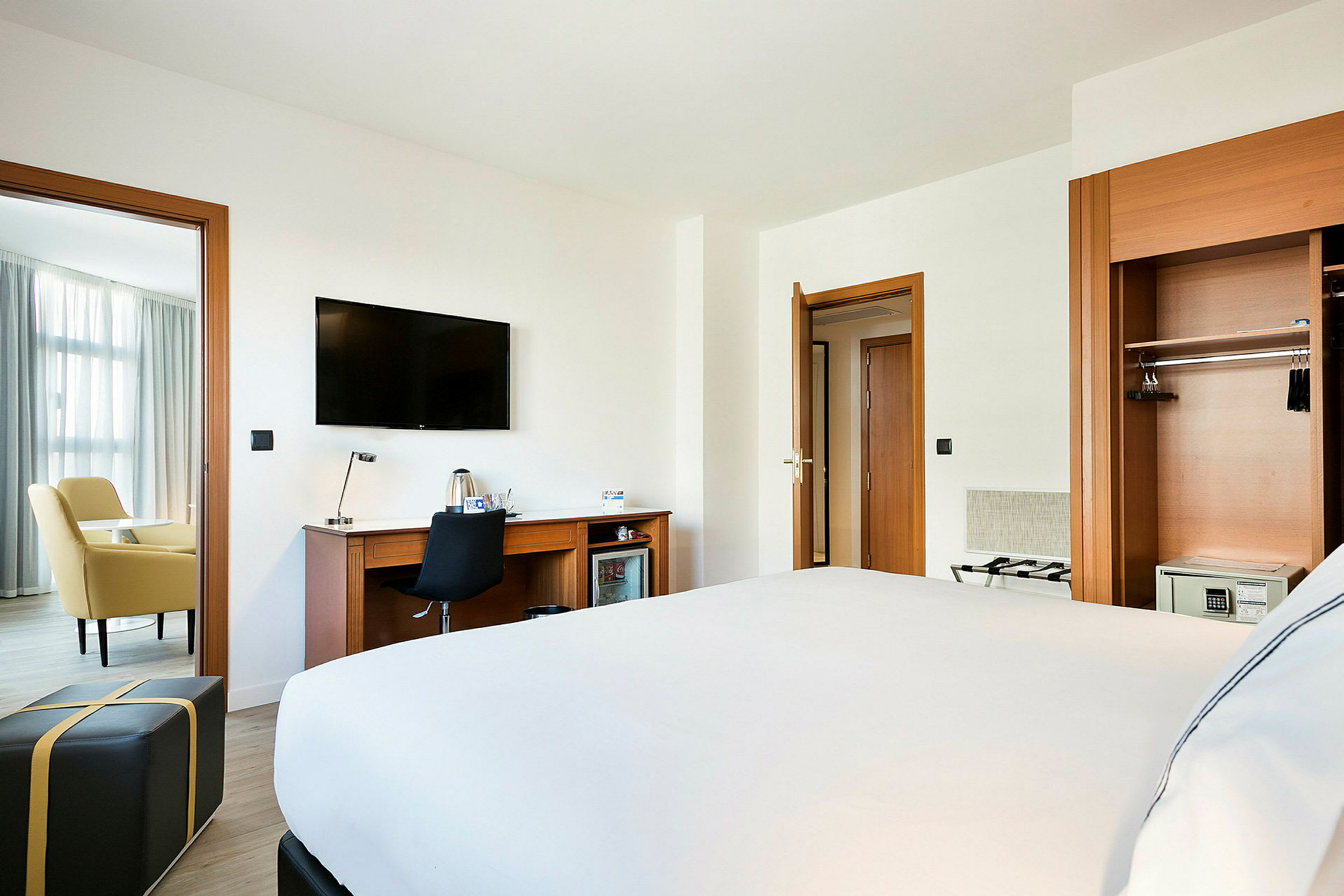 Hotelværelse med en seng, skrivebord, TV og siddeområde. (AI-genereret tekst)