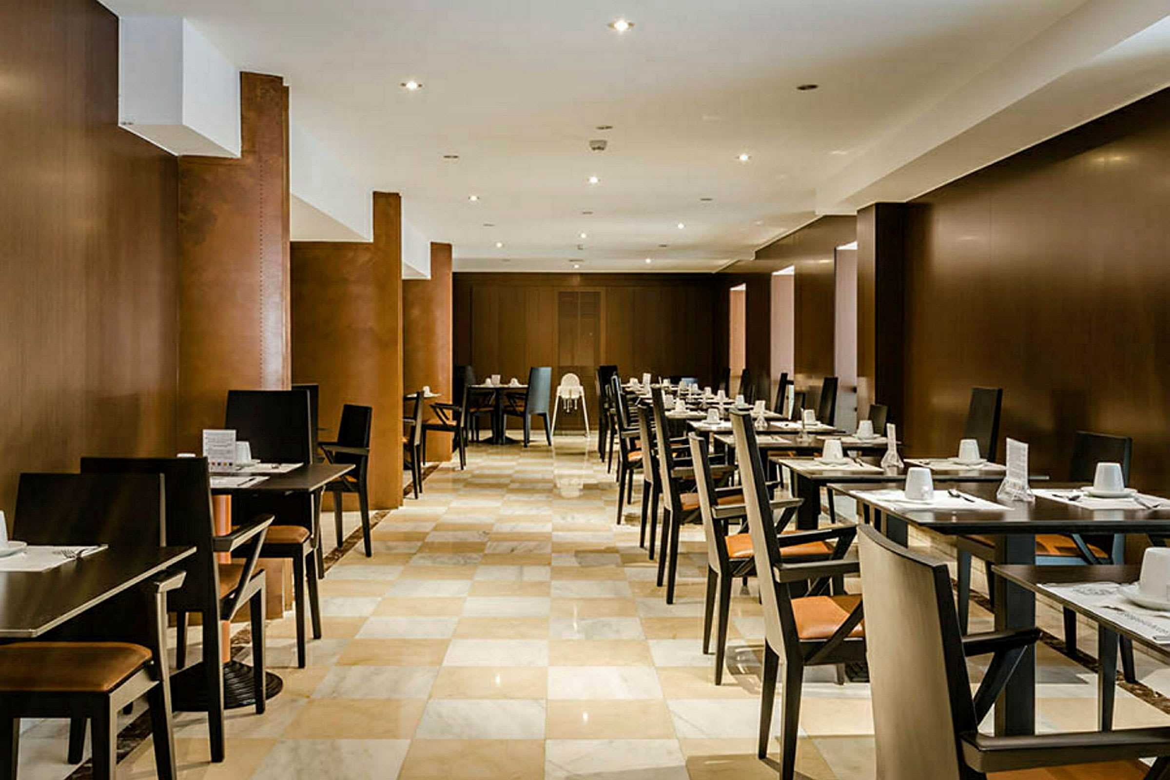 Et restaurantområde med rækker af borde og stole, dækket til gæster. (AI-genereret tekst)