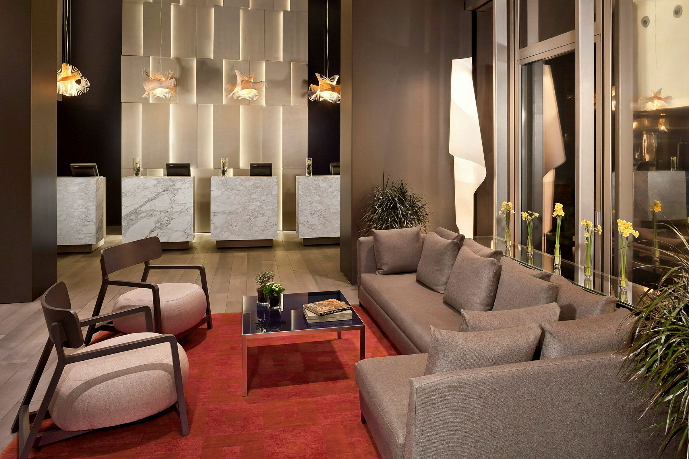 Billede af en hotellobby med marmordiske, moderne sofaer og lænestole samt dekorative lamper. (AI-genereret tekst)