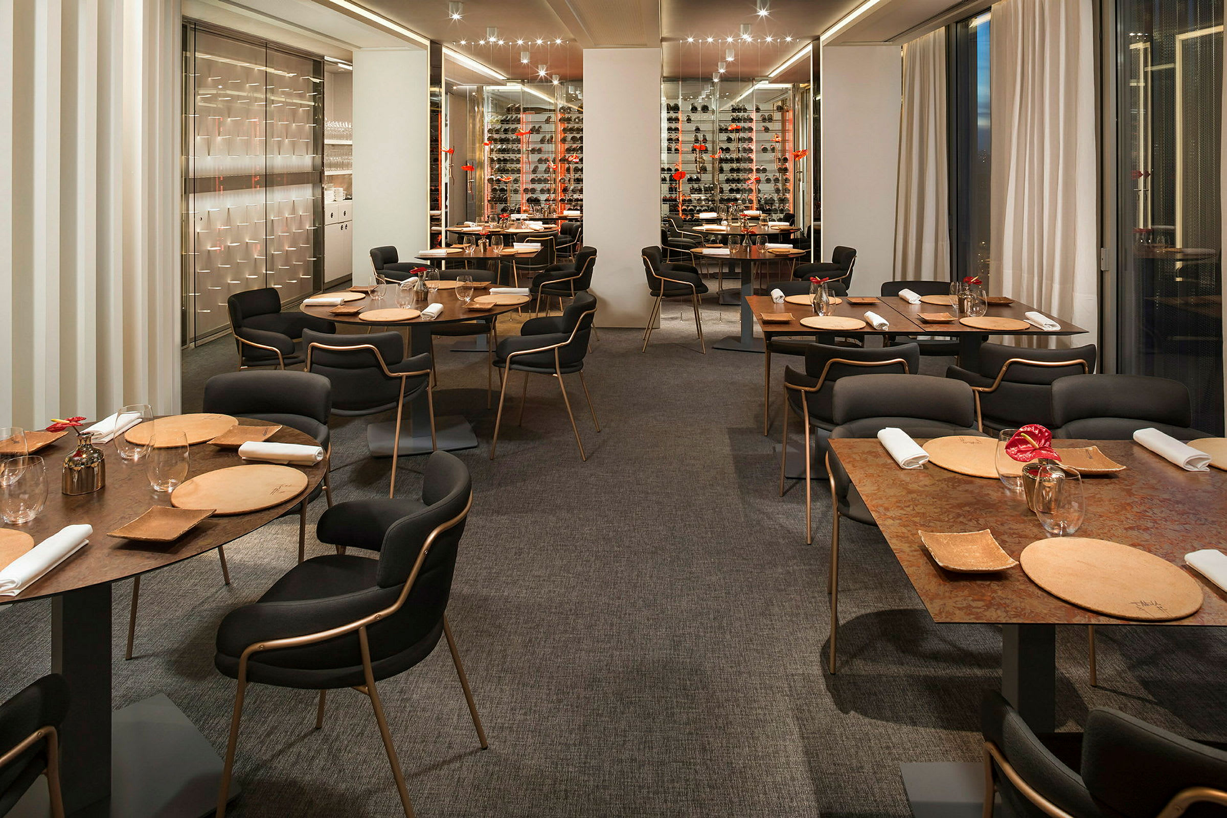 En restaurant med moderne indretning, borde dækket med tallerkener, glas og servietter. (AI-genereret tekst)