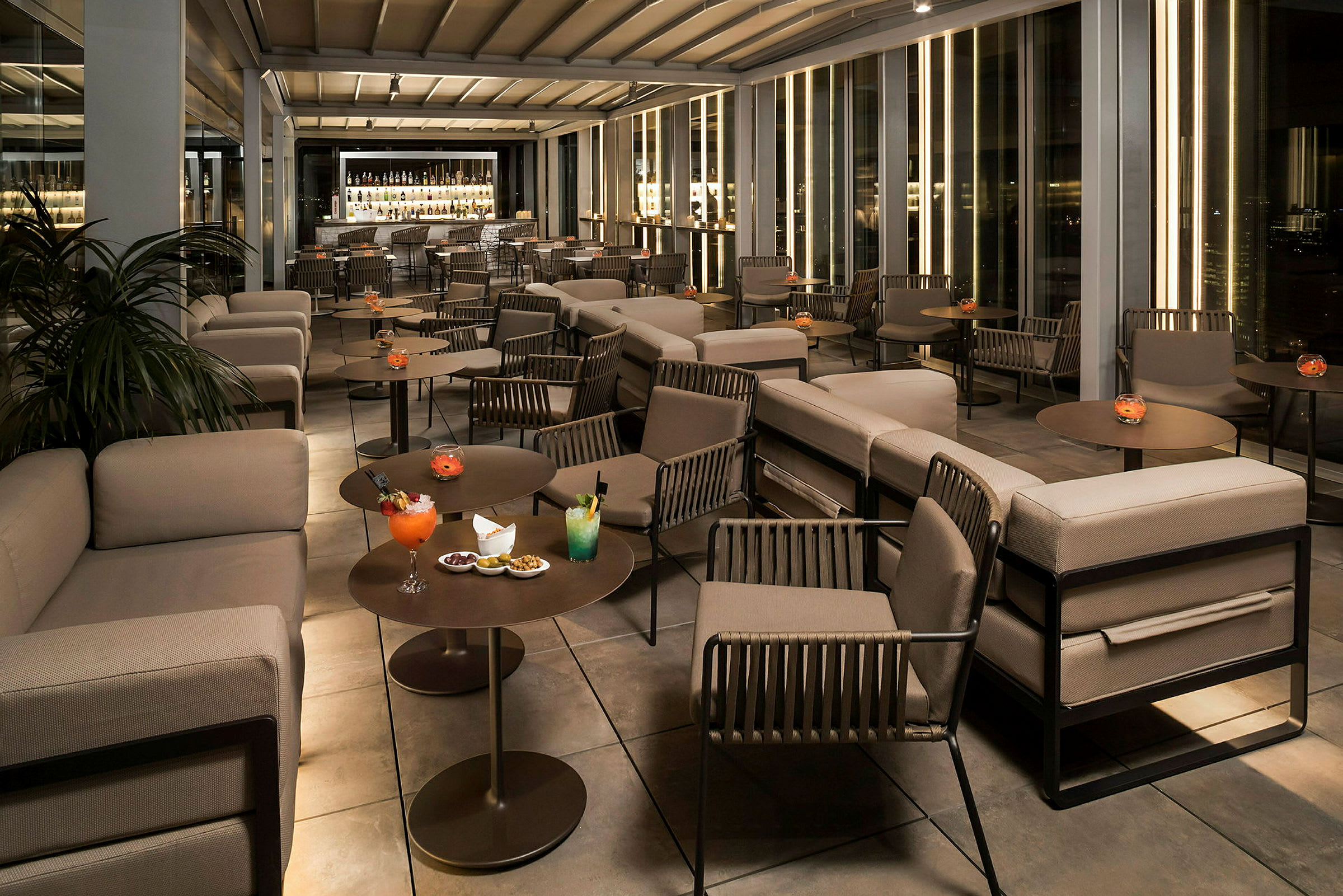 En moderne lounge med sofaer, borde og drikkevarer på et elegant sted. (AI-genereret tekst)